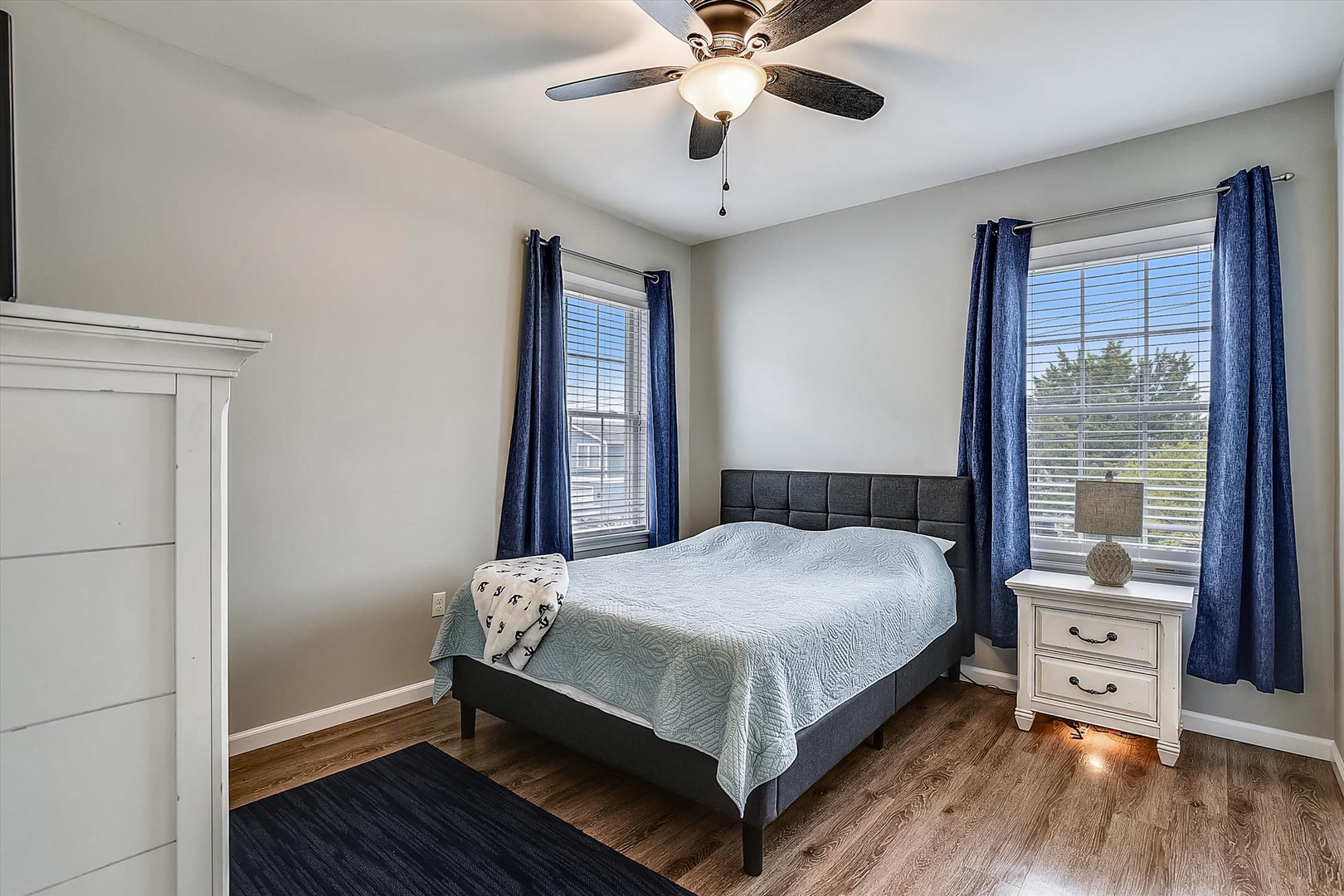 Unwind in your serene bedroom with plush bedding, natural light streaming through dual windows, and a ceiling fan keeping you cool all night.