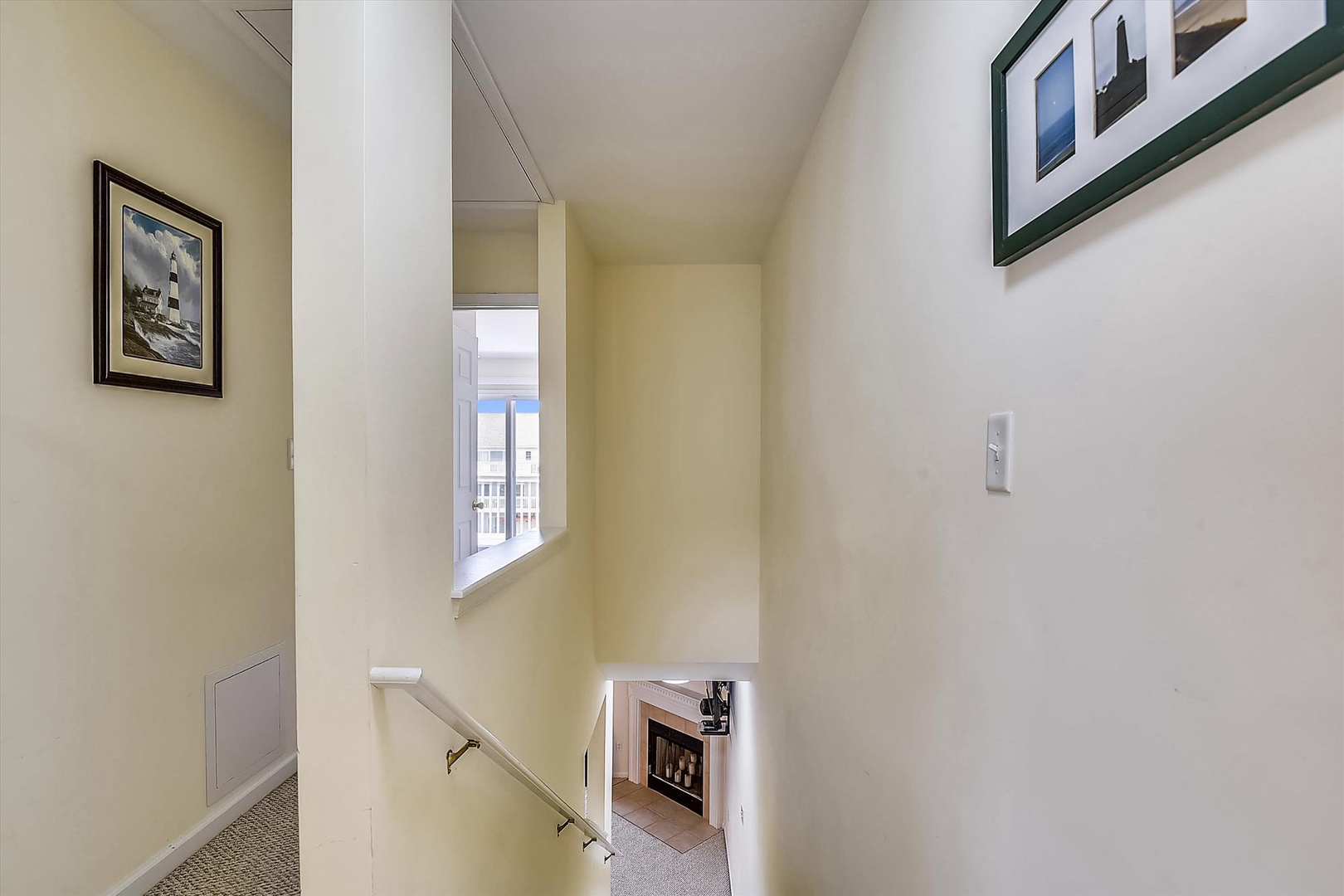 Thoughtfully designed hallway connects living spaces with coastal-themed artwork and natural light from upper-level windows.