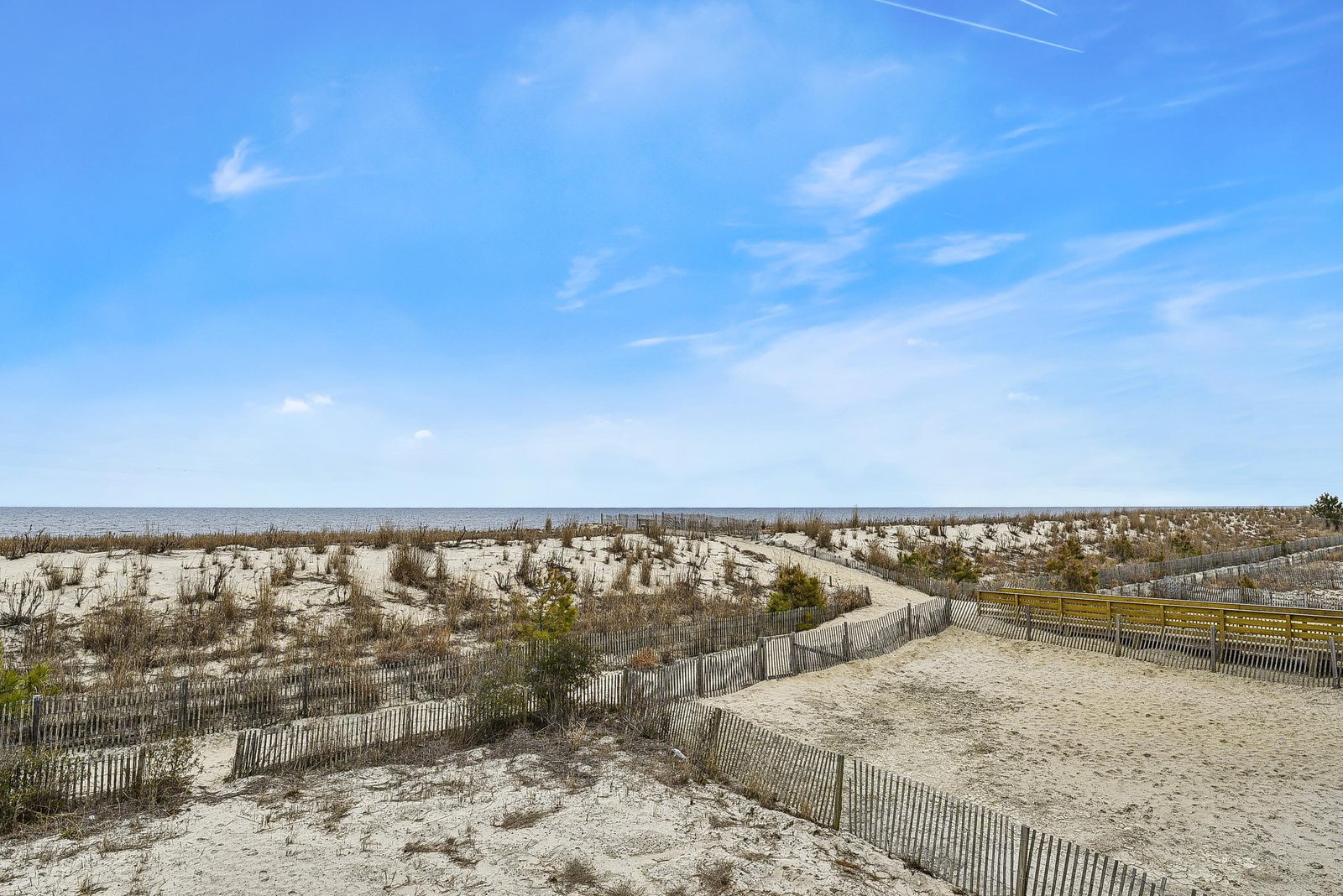 Sandy dunes and coastal pathways lead to the ocean, defining the property's beachfront location and natural surroundings.