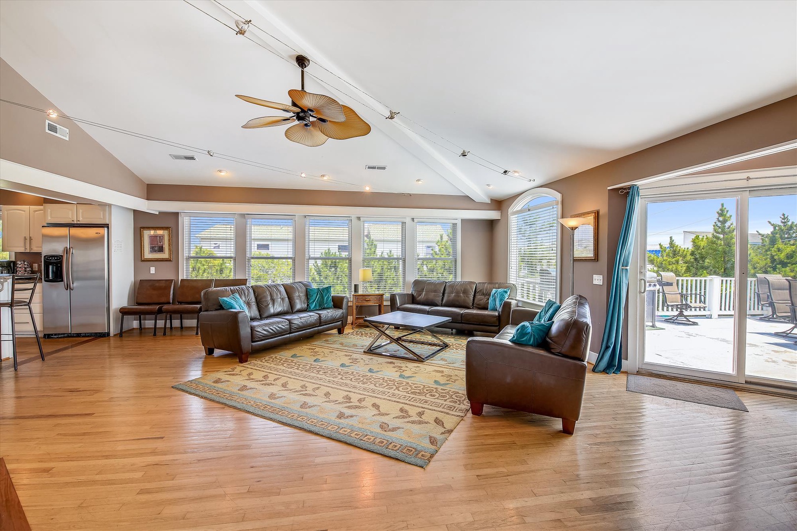 Settle into this sun-drenched living room, where plush leather seating invites you to unwind beneath the tropical ceiling fan. Floor-to-ceiling windows frame tranquil garden views, while sliding glass doors open to your private deck, blending indoor comfo