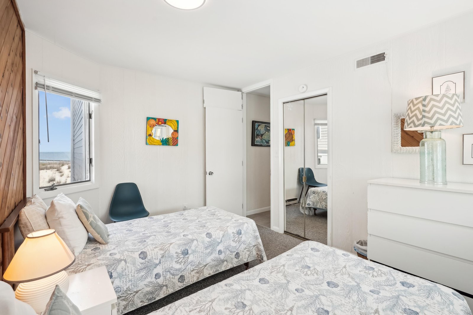 Wake up to soft coastal breezes and serene beach views framed by your bedroom window. Two cozy beds, cheerful artwork, and a peaceful ambiance create your perfect seaside retreat.