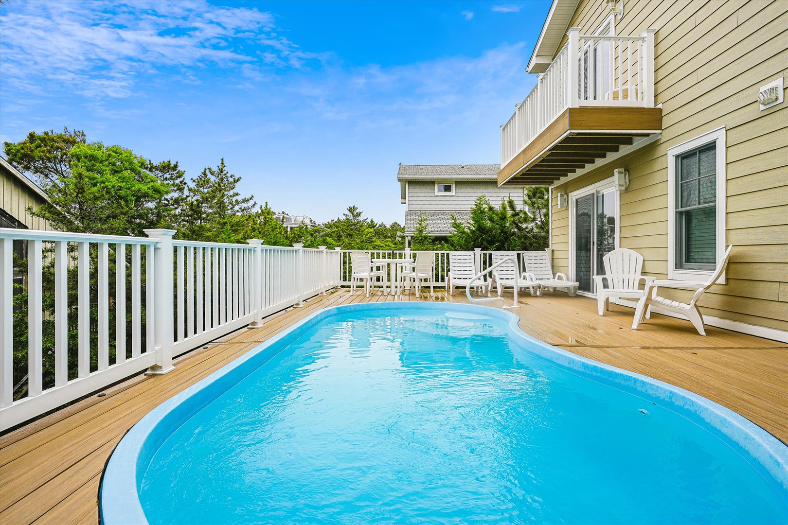 Imagine cooling off in your private pool on this sun-drenched deck, complete with lounge chairs and a peaceful backdrop of greenery and coastal charm—perfect for pure vacation bliss.