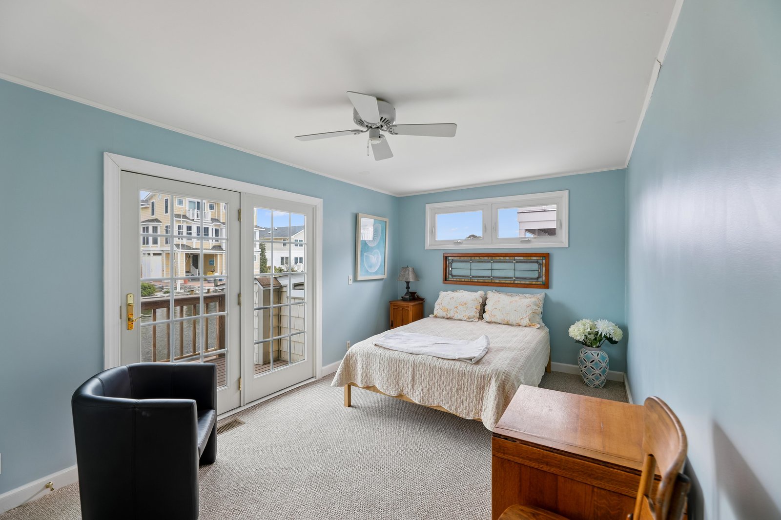 Unwind in your peaceful bedroom with French doors opening to outdoor space. Soft coastal blue walls and a cozy bed invite restful sleep after your beachside adventures.