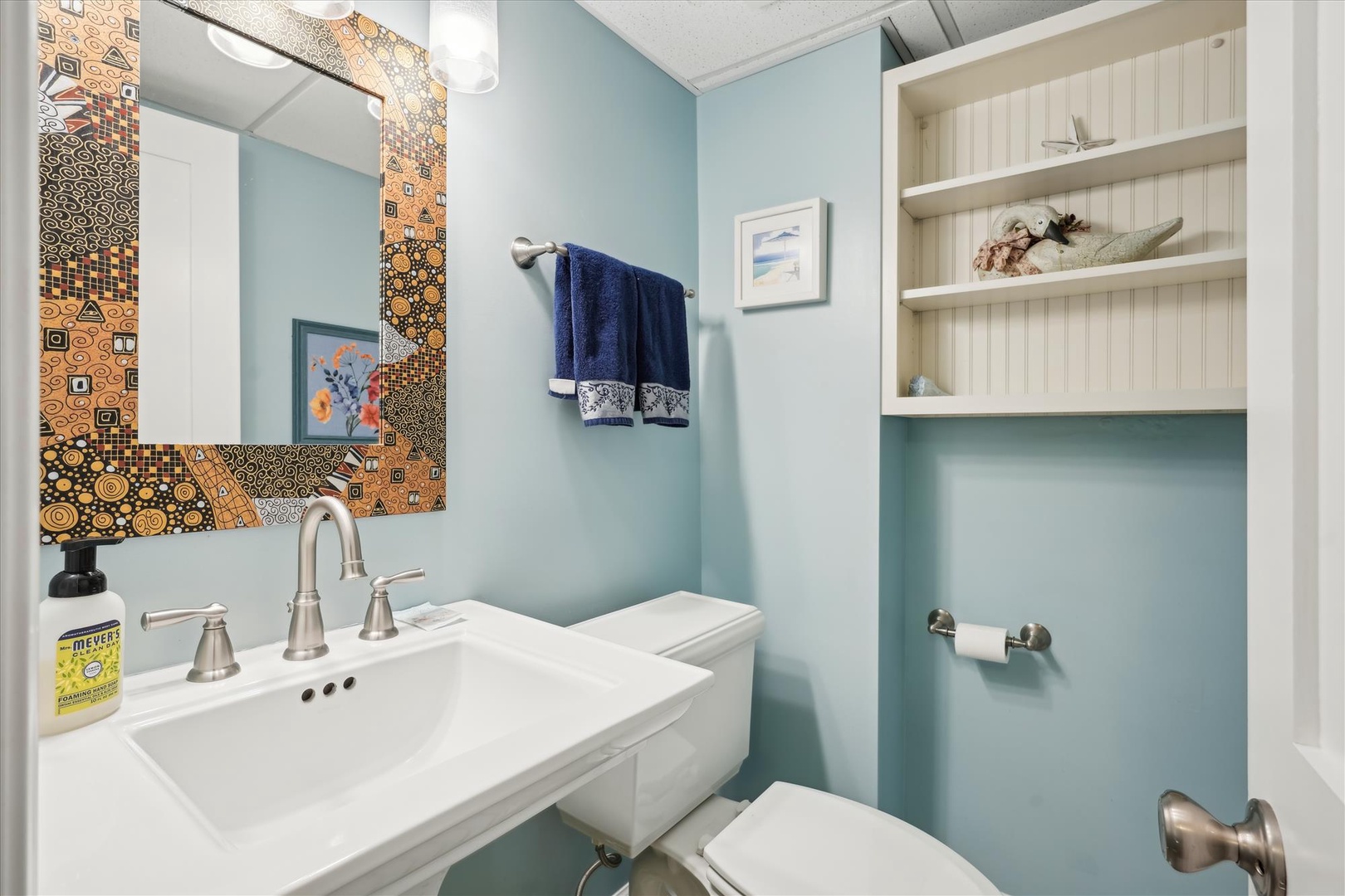 Refresh in your charming bathroom featuring colorful mosaic details, soft blue walls, and thoughtful storage for your essentials.