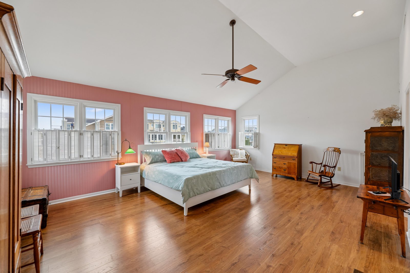 Unwind in this bright, spacious bedroom with vaulted ceilings, gleaming hardwood floors, and cozy vintage wood furnishings. Soft natural light and a cooling ceiling fan create your perfect retreat.