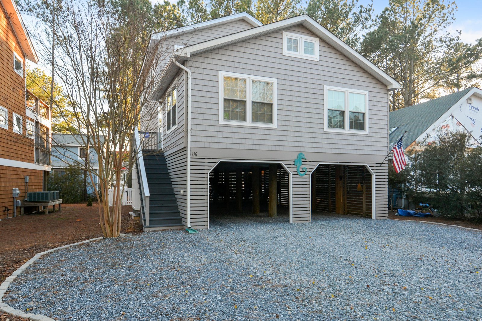 Coastal-style retreat with convenient parking and welcoming outdoor space, nestled among mature trees in a peaceful neighborhood.