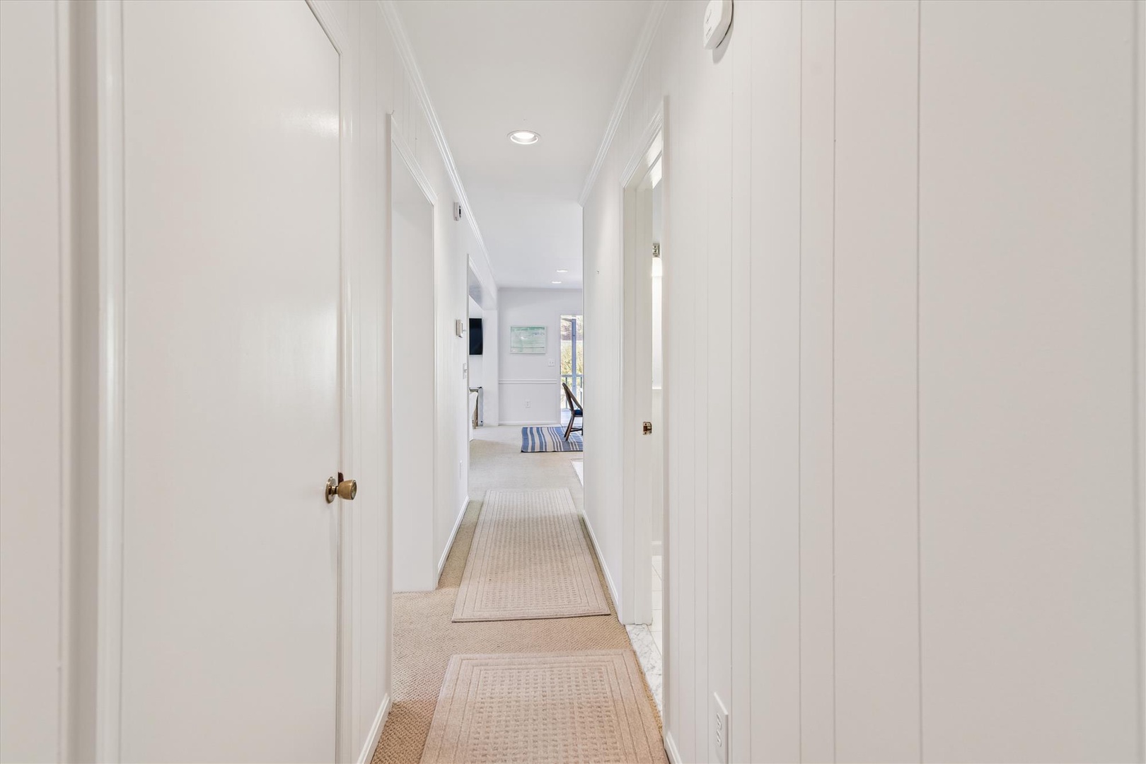 Step into your bright hallway leading to comfortable living spaces, with crisp white walls and warm rugs underfoot.