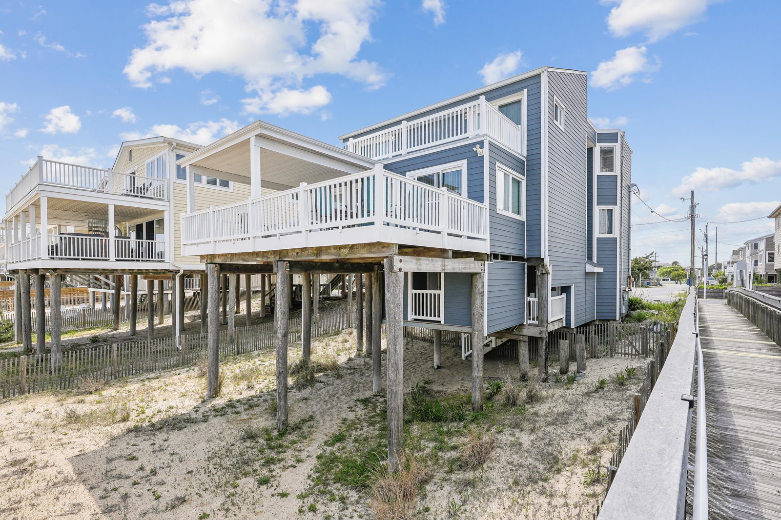 Elevated beachfront homes on stilts with sandy dunes and a boardwalk leading to the shore—your coastal retreat awaits just steps from the water.