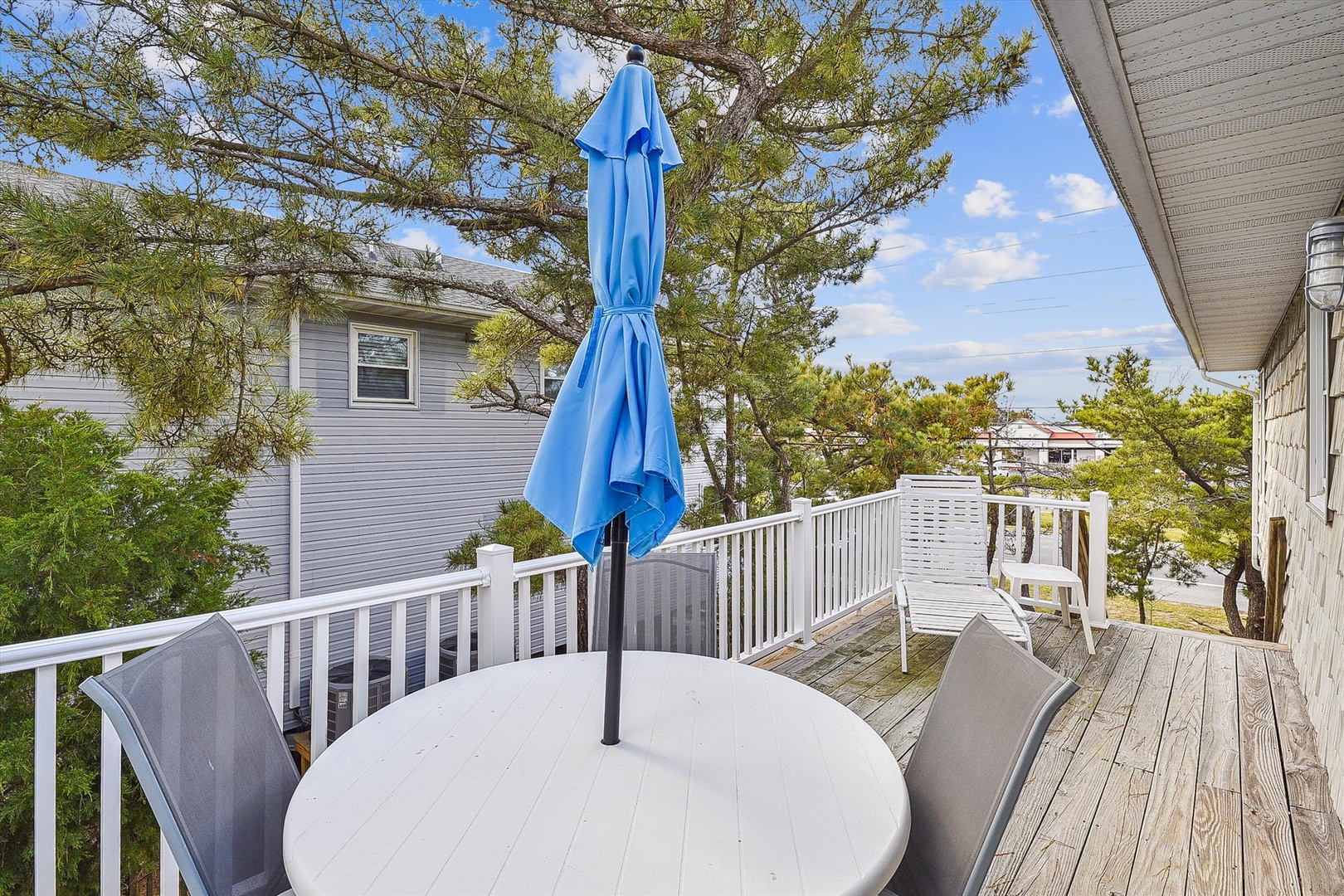 A spacious deck framed by trees and blue skies, perfect for your morning coffee or evening unwinding with a view of the peaceful neighborhood.