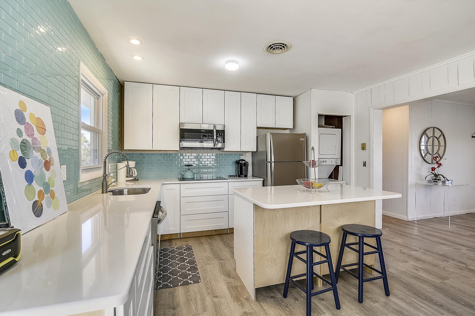Step into your fully-equipped kitchen with stylish turquoise tile backsplash, modern appliances, and a breakfast bar—perfect for preparing meals and gathering together over morning coffee.