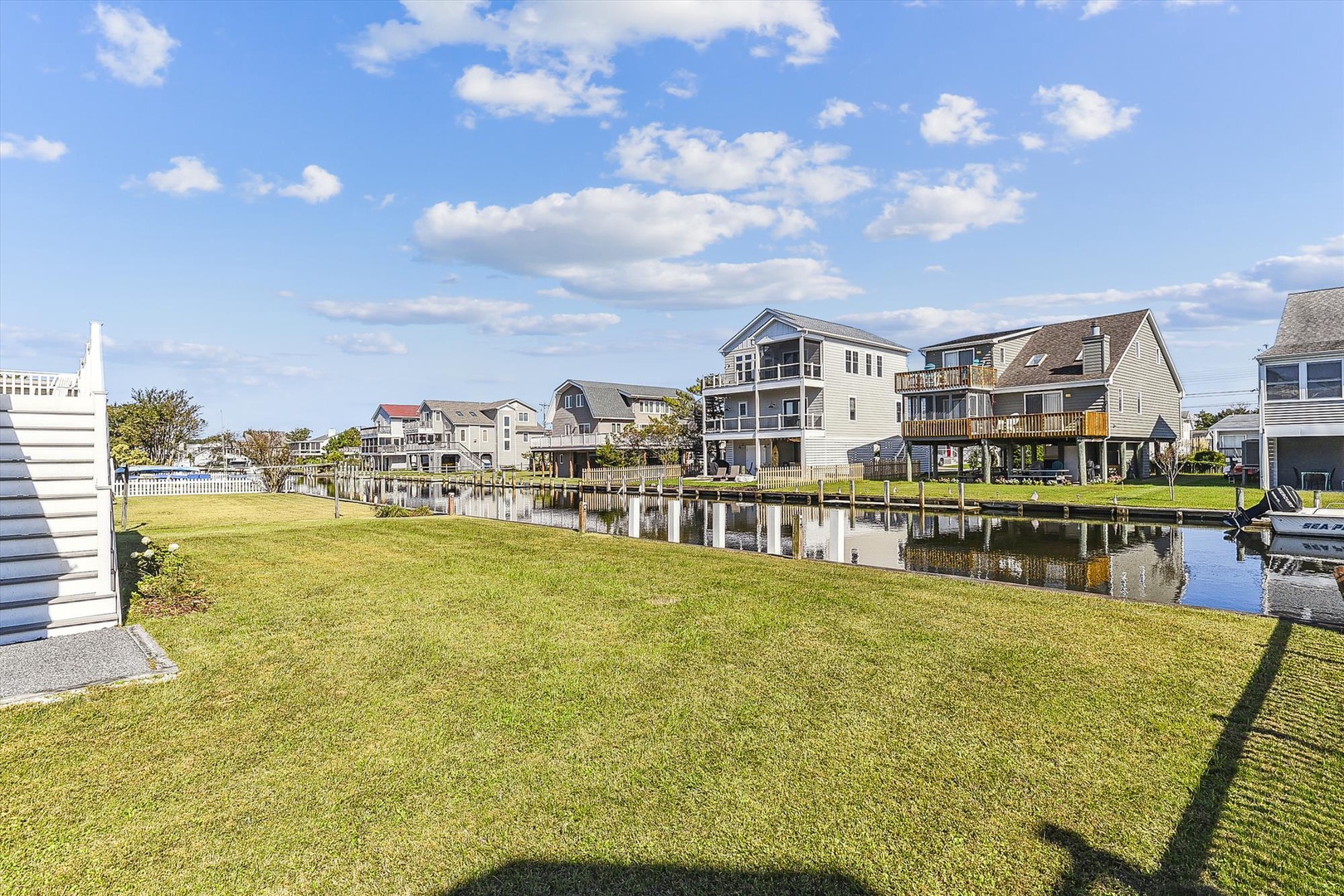 Waterfront neighborhood featuring canal-side homes with private boat docks, surrounded by lush lawns and scenic water views under a bright sunny sky.