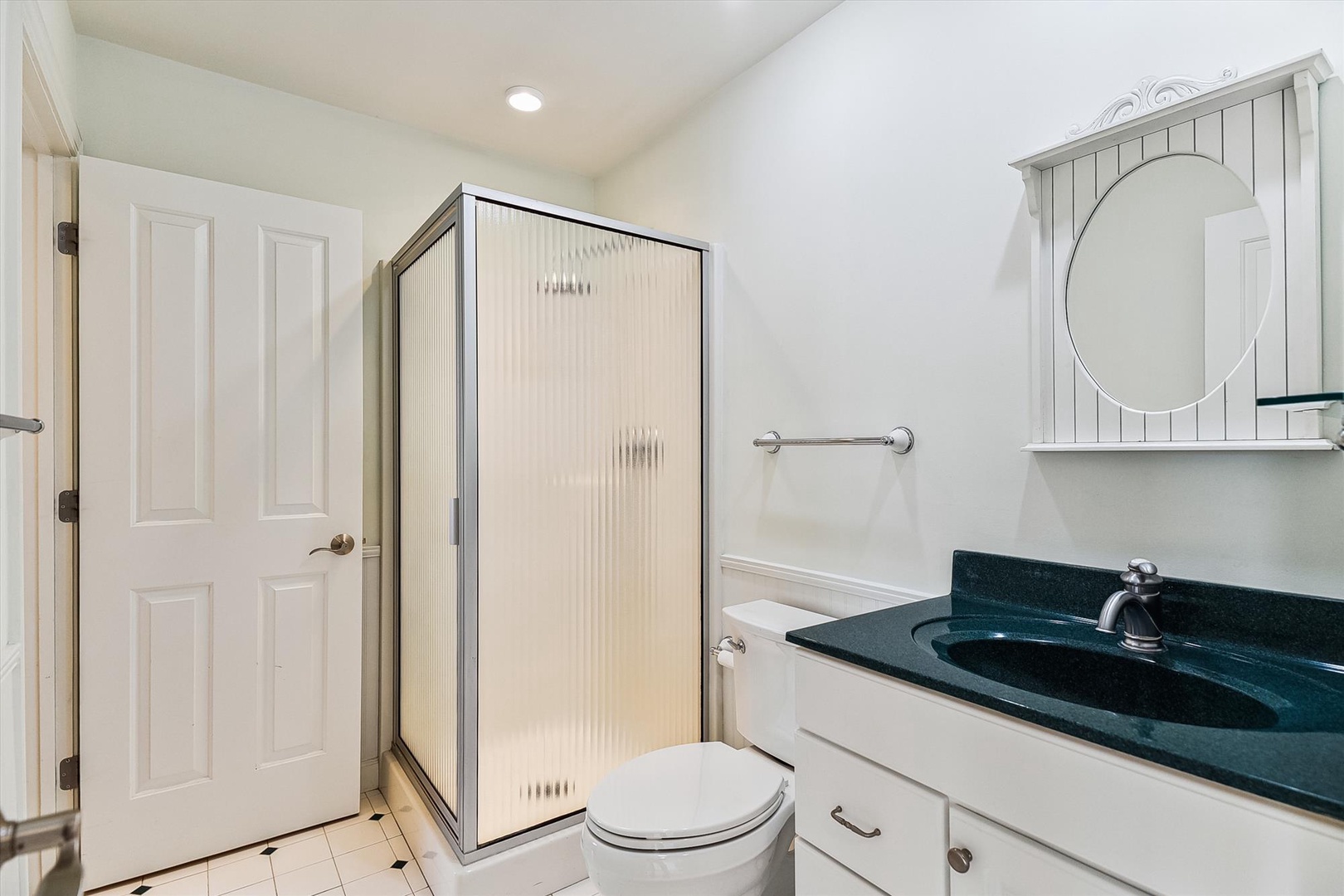 Your private bathroom features a spacious walk-in shower, elegant deep green countertops, and a coastal-inspired mirror—making it easy to freshen up after a day at the beach.