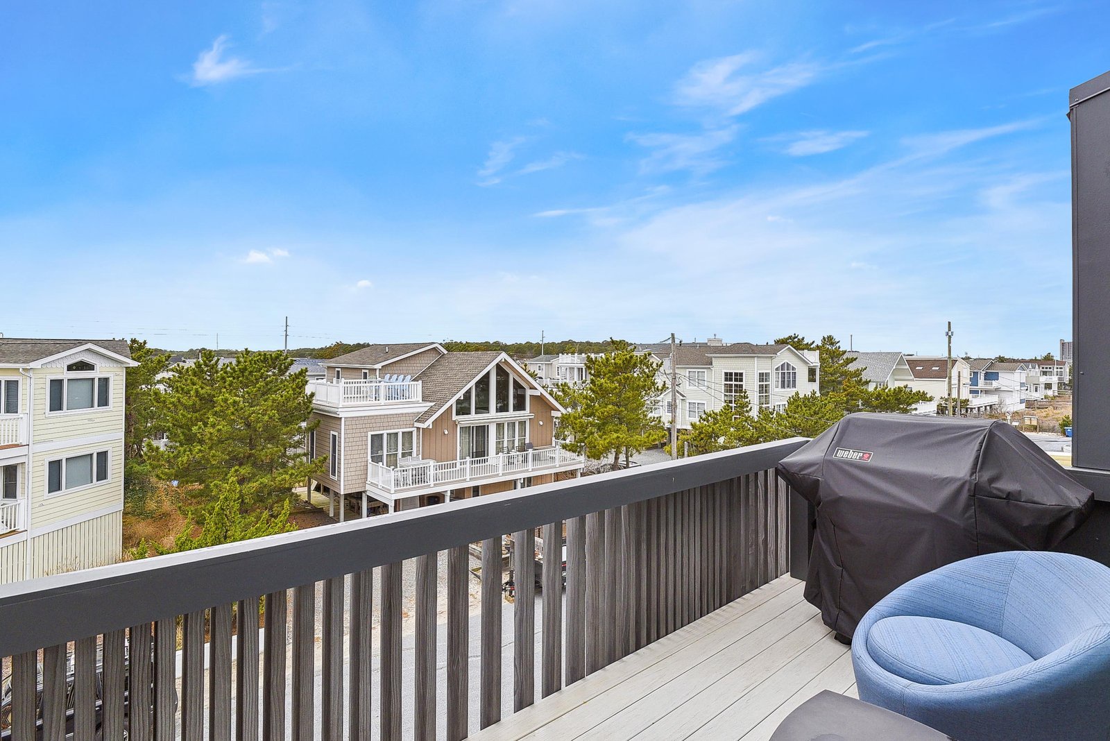 A bright coastal neighborhood spreads before your rooftop deck, where you can grill under open skies and watch the day unfold from your private retreat.