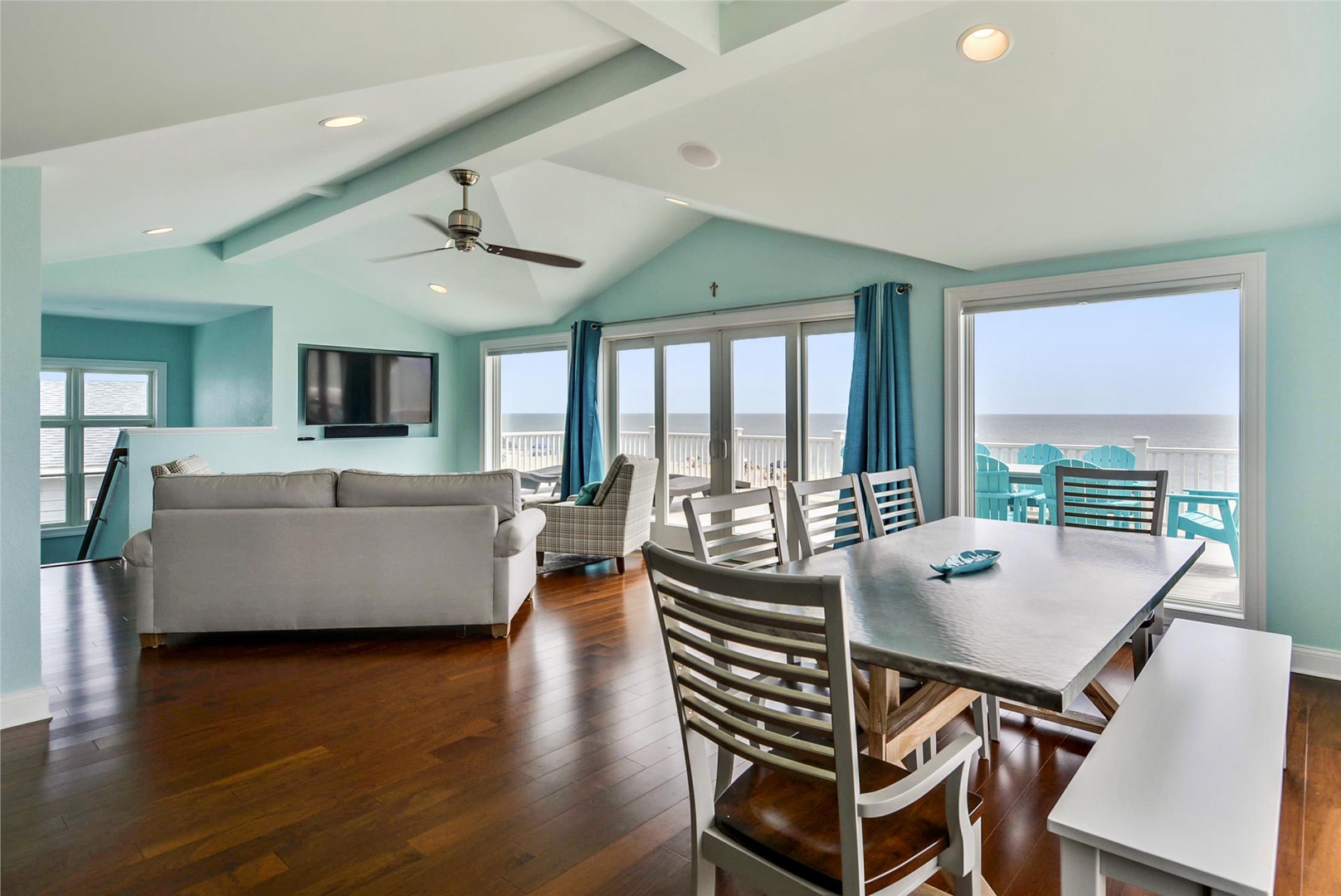 Imagine gathering around this bright, open dining and living space where turquoise coastal hues mirror the ocean views beyond. Your mornings begin here with coffee and breathtaking vistas, while evenings unwind on the balcony overlooking endless sea.