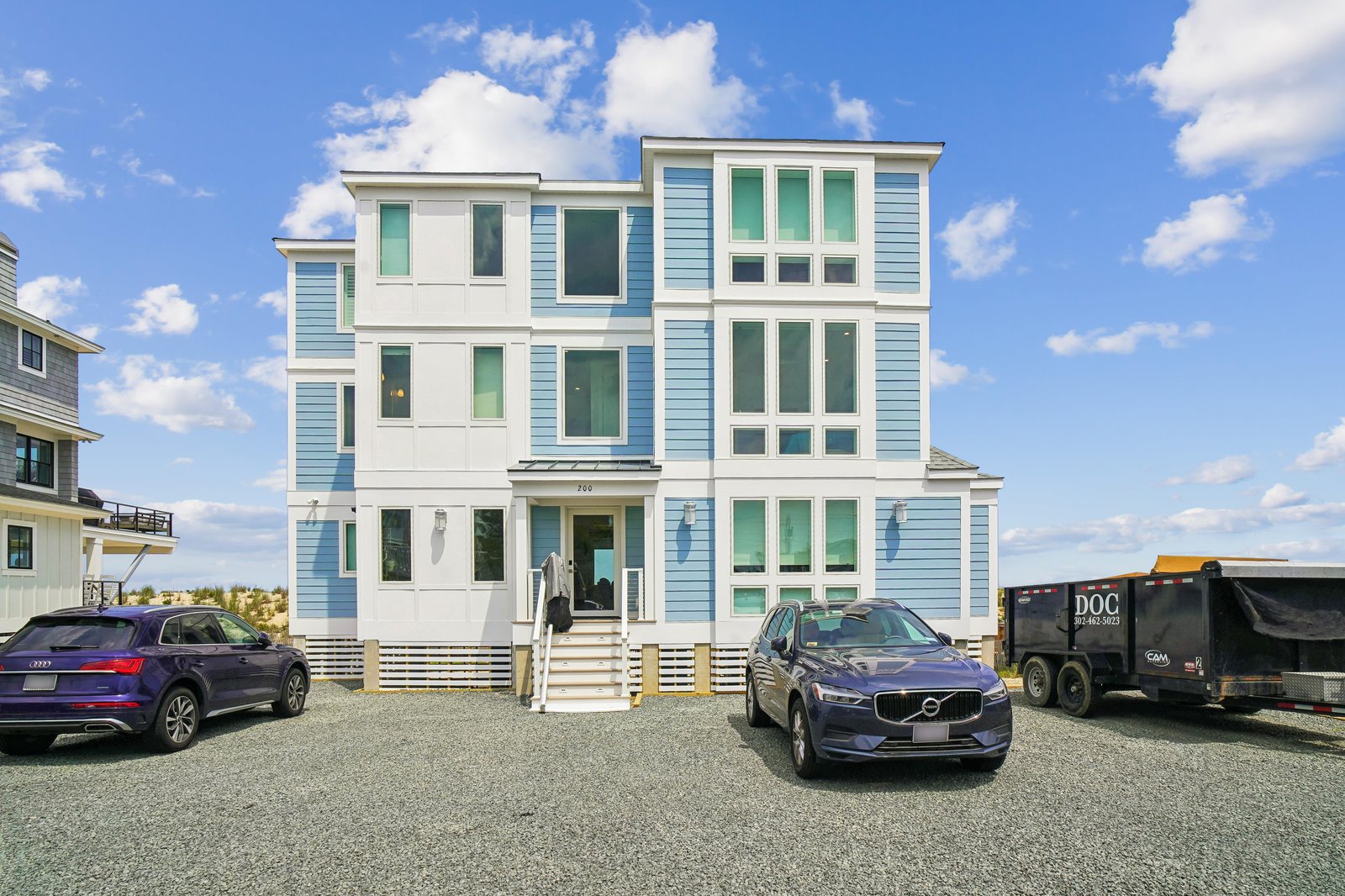 This modern beach house welcomes you with airy coastal charm, featuring crisp blue and white siding, spacious parking, and a bright, open design perfect for your getaway.