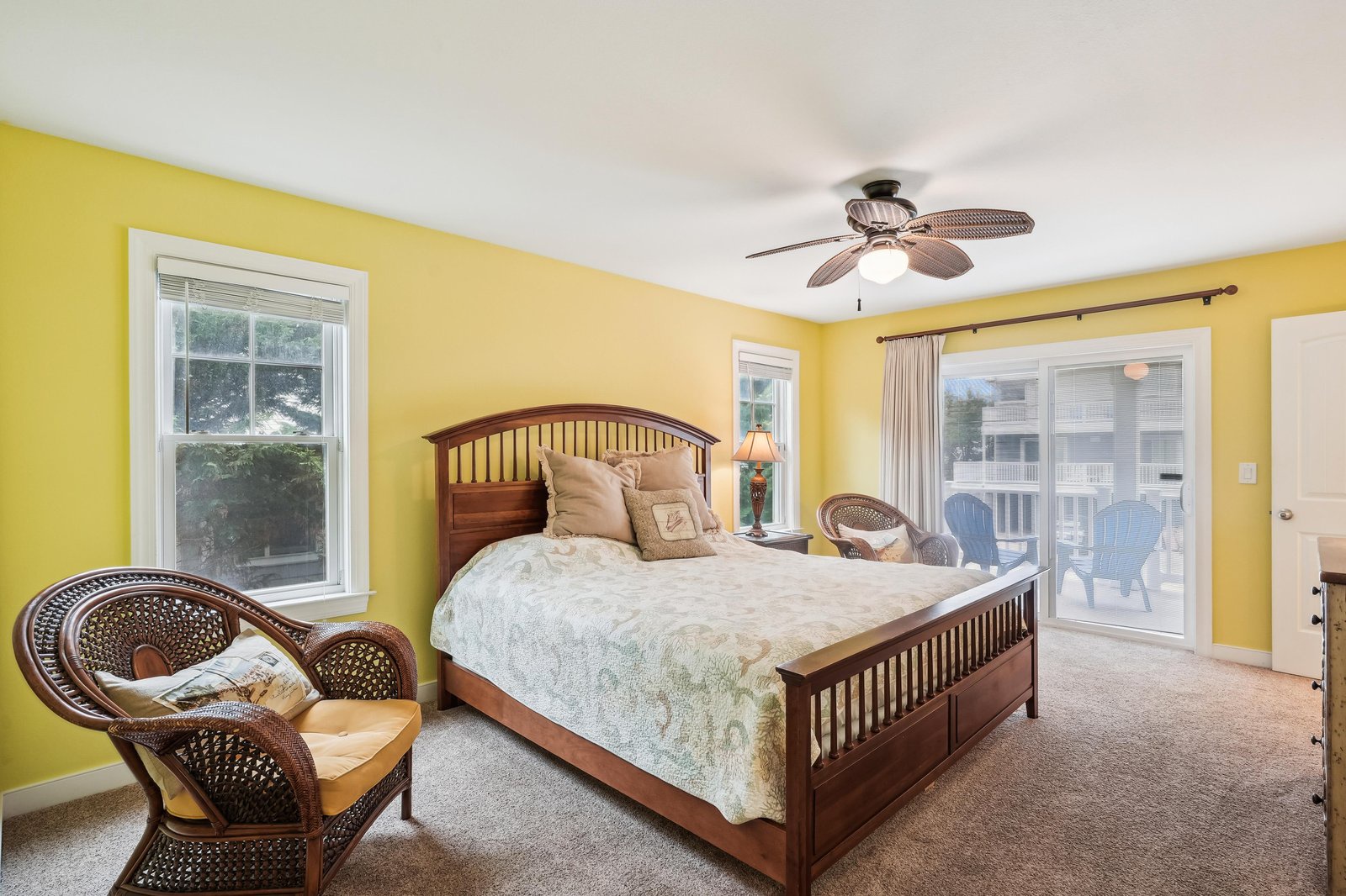 Unwind in your sunny bedroom with charming wicker seating and direct balcony access—your personal retreat awaits.