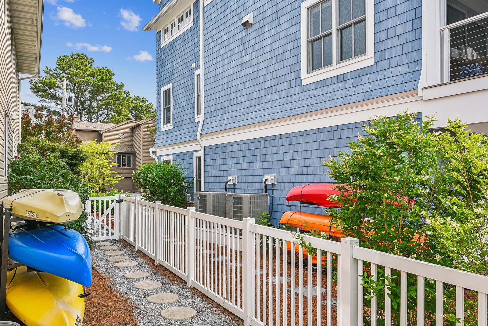 A charming side path with colorful kayaks ready for your next water adventure. The fenced walkway connects you to the main entrance through lush greenery.
