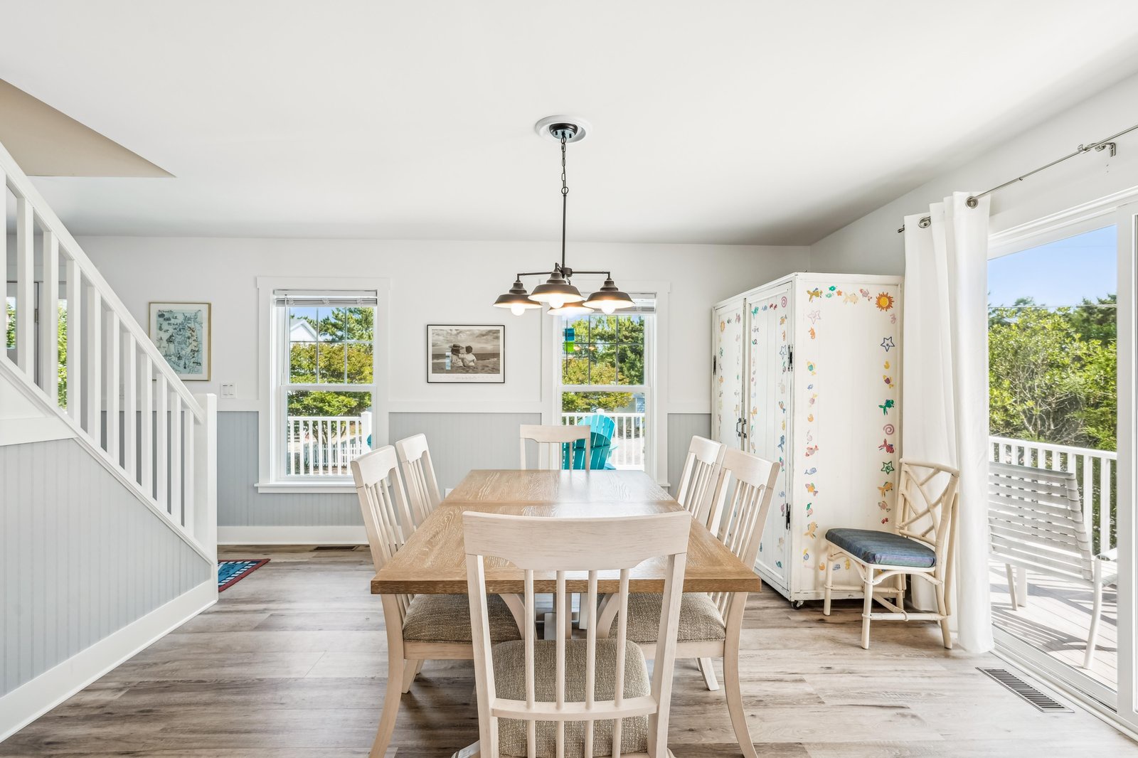 Step into your sun-filled dining space, where large windows frame views of lush greenery and invite natural light throughout the day. Gather around the welcoming table for shared meals while the coastal breeze flows through open balcony doors.