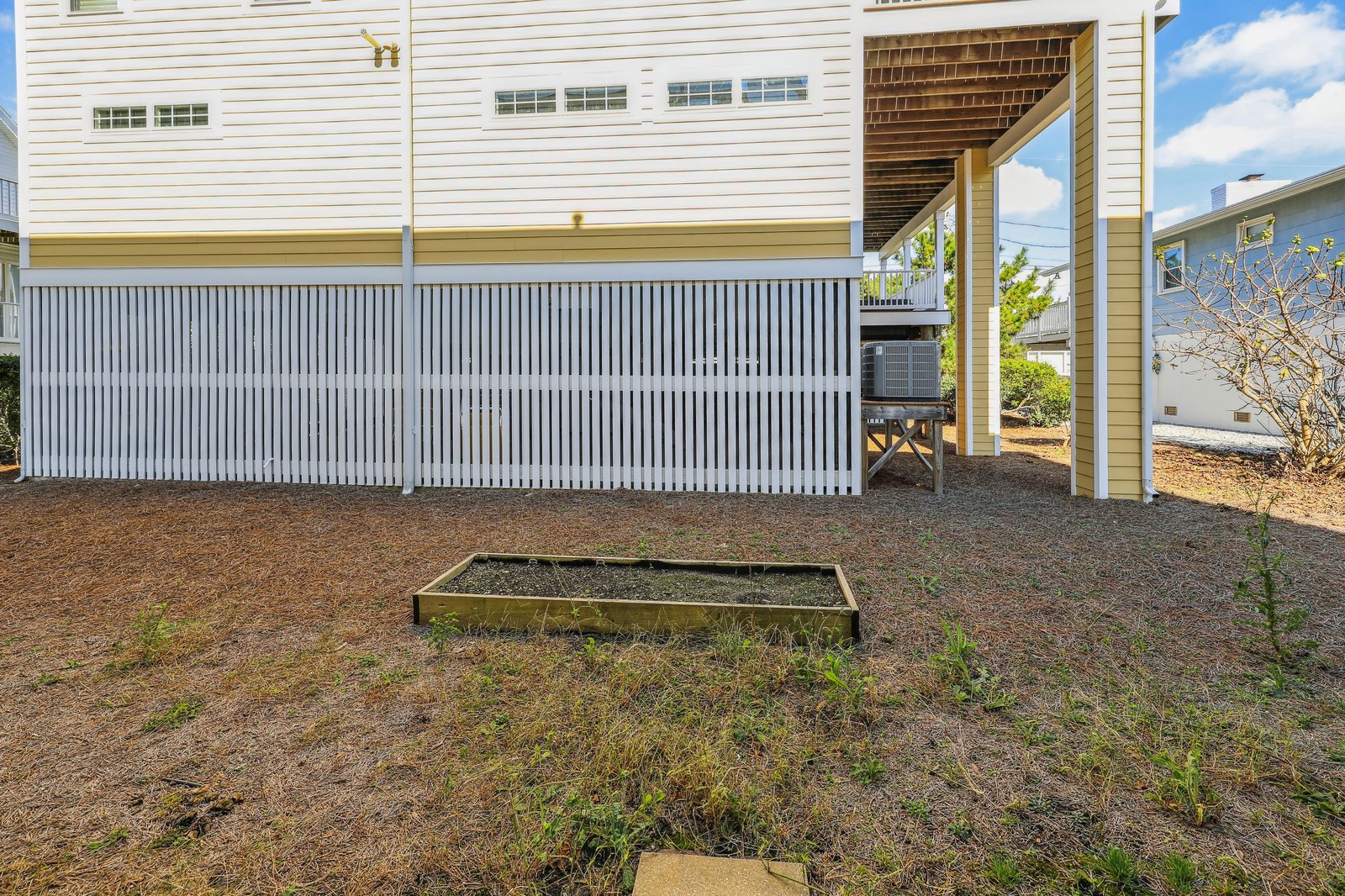 Private backyard with raised garden bed, covered deck, and barbecue area—your outdoor space for grilling and relaxing under open skies.