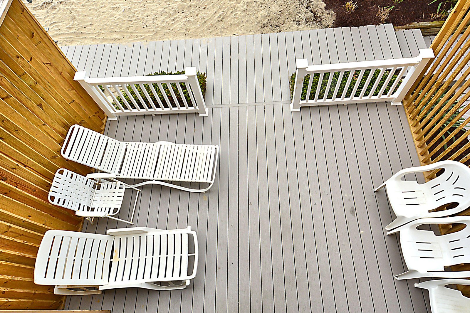 A spacious deck overlooks the sandy beach, offering white lounge chairs where you can soak up the sun just steps from the shore.