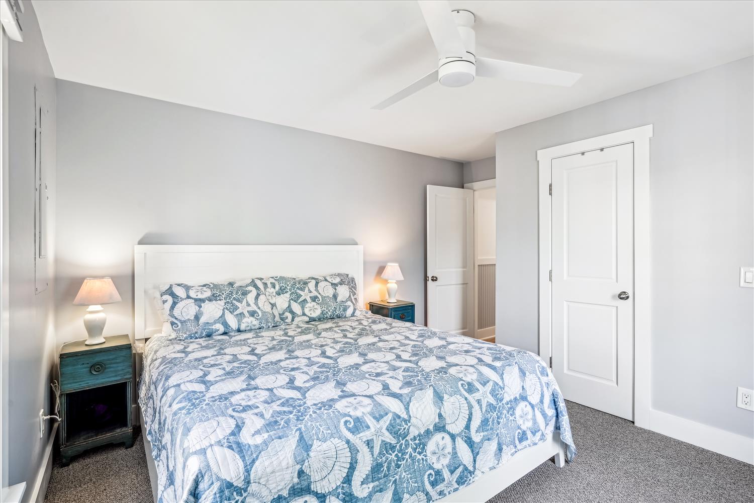Drift off in your serene bedroom featuring coastal-inspired linens and gentle ceiling fan breezes for perfect comfort.