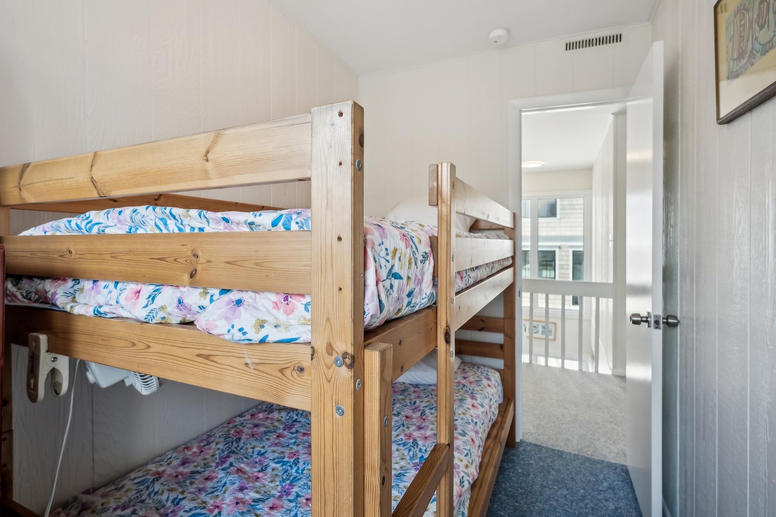 Your kids will love this cozy bunk room with two sets of sturdy wooden bunks, each dressed in cheerful, colorful bedding, and bright white walls that fill the space with light.