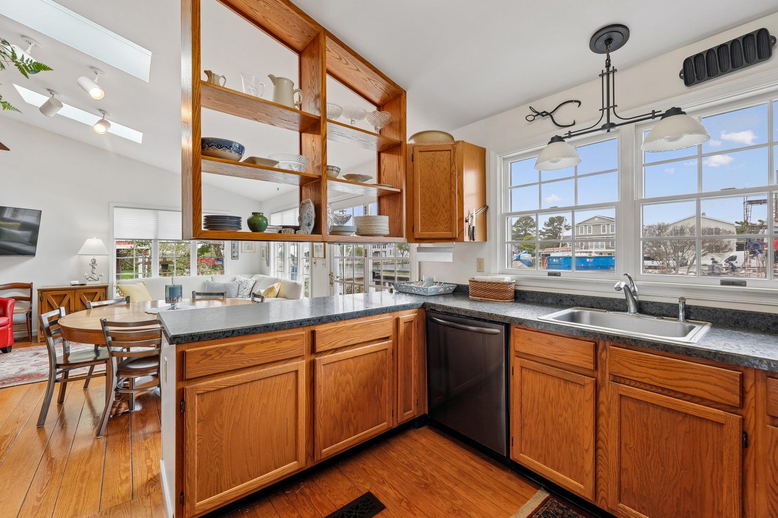 Step into a bright, open kitchen with warm wood cabinetry and sleek granite counters. Natural light pours through wide windows, and the open layout flows effortlessly into your dining and living spaces—perfect for gathering and making memories.