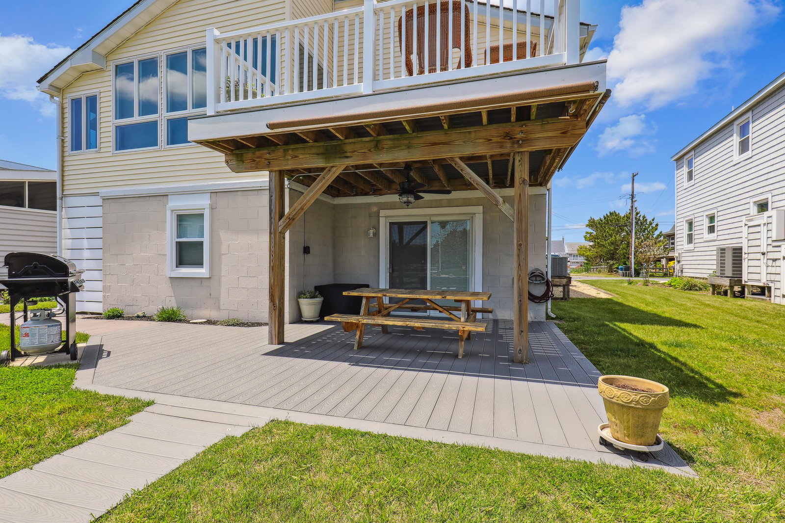 A covered patio with a picnic table invites outdoor meals and relaxation. Above, your private balcony awaits, while the BBQ grill promises delicious evenings under the open sky.