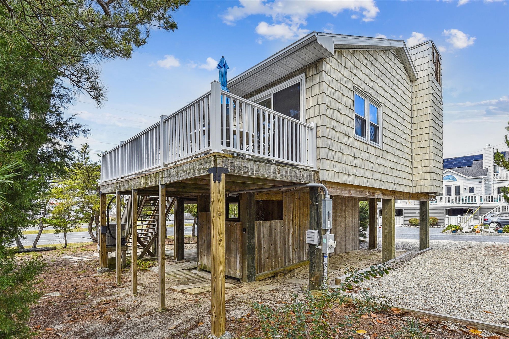Coastal retreat featuring elevated deck and stilted construction, providing convenient beach access in a quiet neighborhood setting with ample parking and nearby waterfront views.
