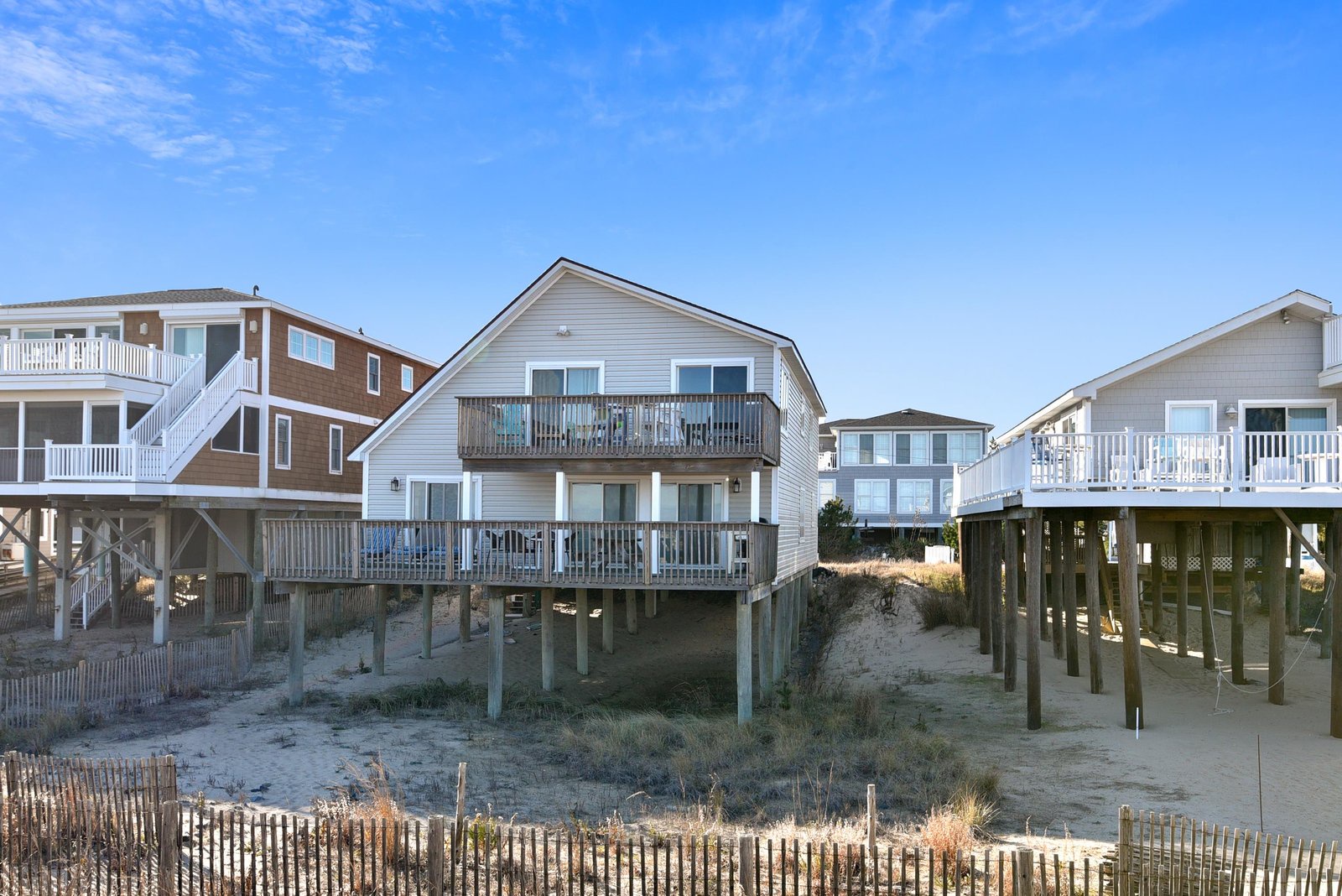A row of coastal vacation homes elevated on sturdy pilings, offering easy access to the sandy beach and dunes just steps from your door.