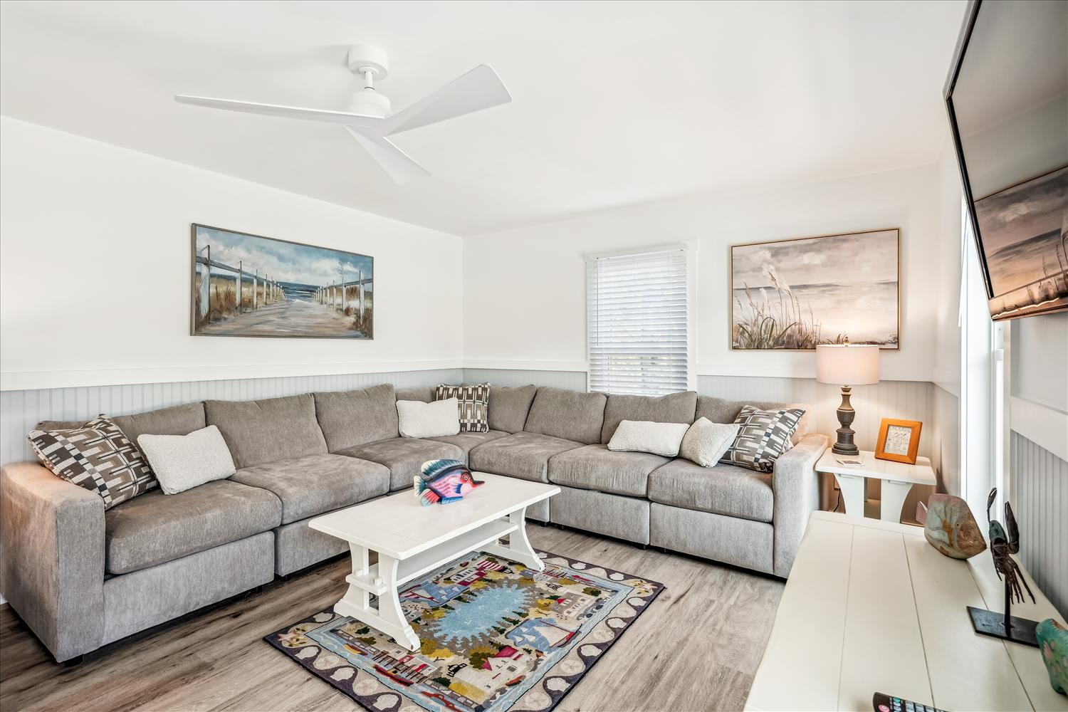 Sink into plush sectional seating in your bright living room, where coastal artwork and modern comfort create the perfect retreat.