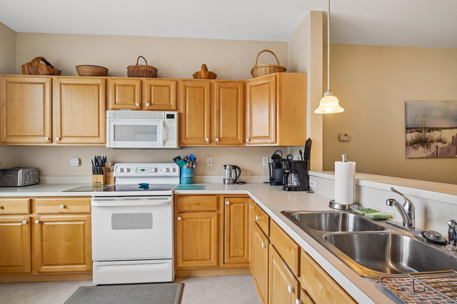 Your spacious kitchen offers everything you need to prepare home-cooked meals, with warm wood cabinetry, ample counter space, and modern appliances including a coffee maker to start your mornings right.