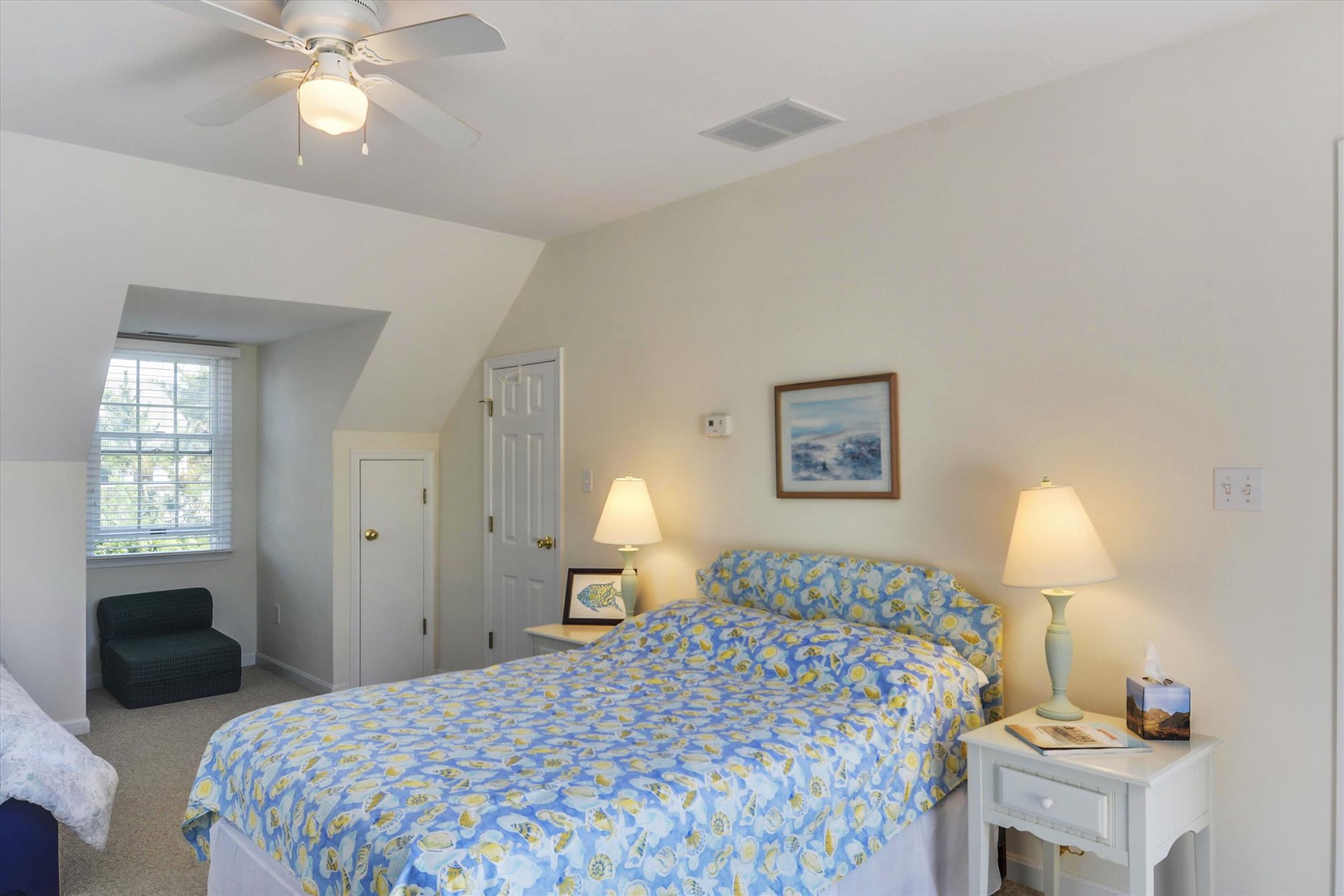 Your bright, serene bedroom welcomes you with soft coastal tones and gentle breezes from the ceiling fan. Sink into the plush bed adorned with cheerful linens, unwind by the lamps, and feel right at home.