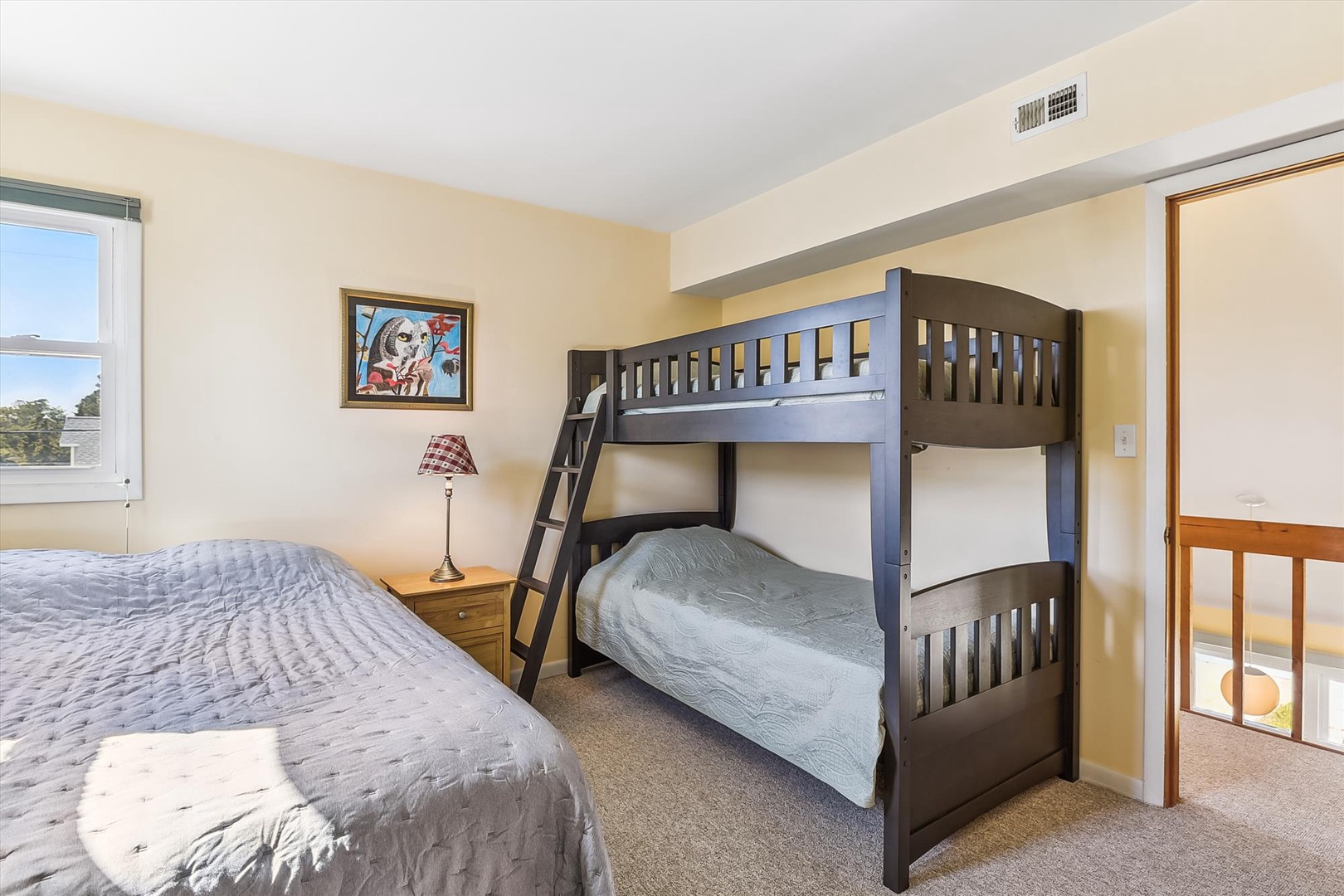 Your cozy bedroom features a queen bed and bunk beds, perfect for families. Soft natural light fills the space, creating a peaceful retreat for restful nights.