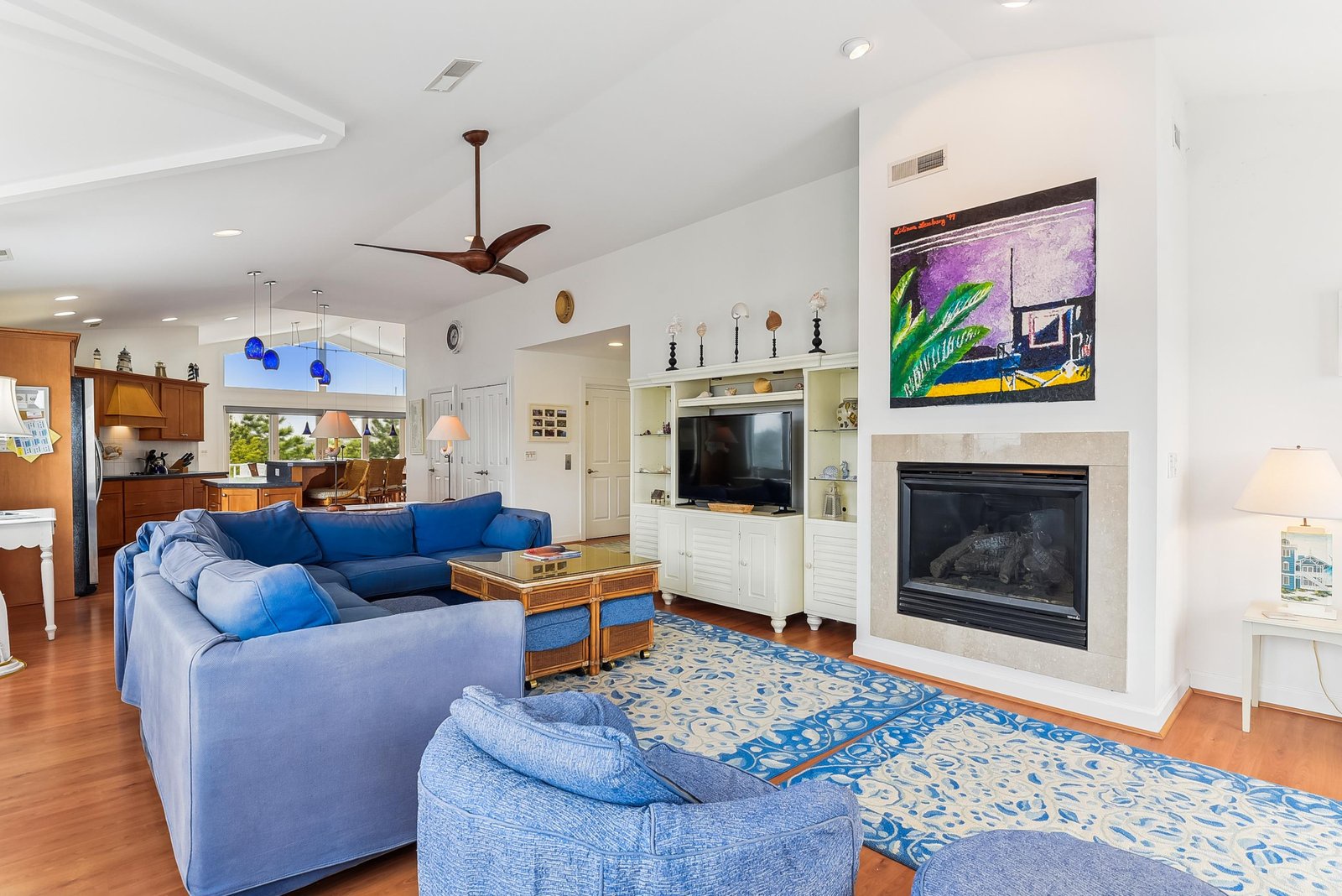 Unwind in your bright, open living space with plush blue seating, a cozy fireplace, and vaulted ceilings that create an airy, coastal vibe perfect for gathering.