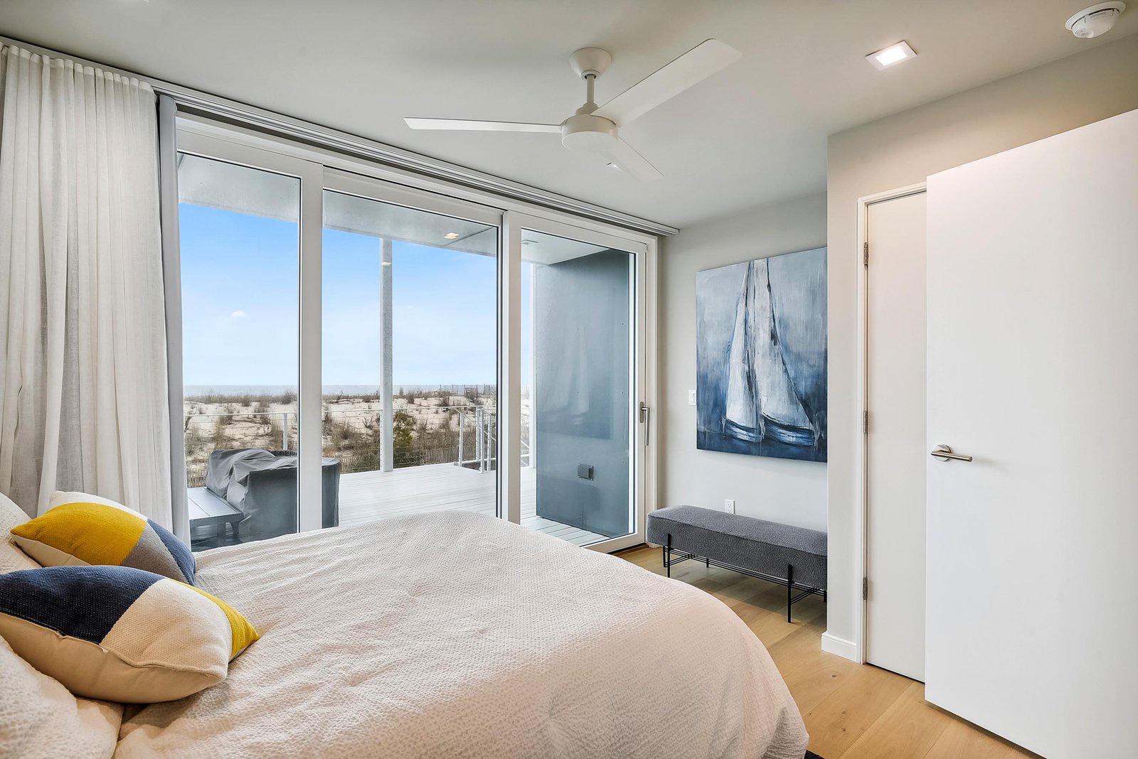 Step through sliding glass doors onto your private balcony and wake up to endless coastal views. This airy bedroom offers a peaceful retreat with soft natural light and cooling ceiling fan overhead.