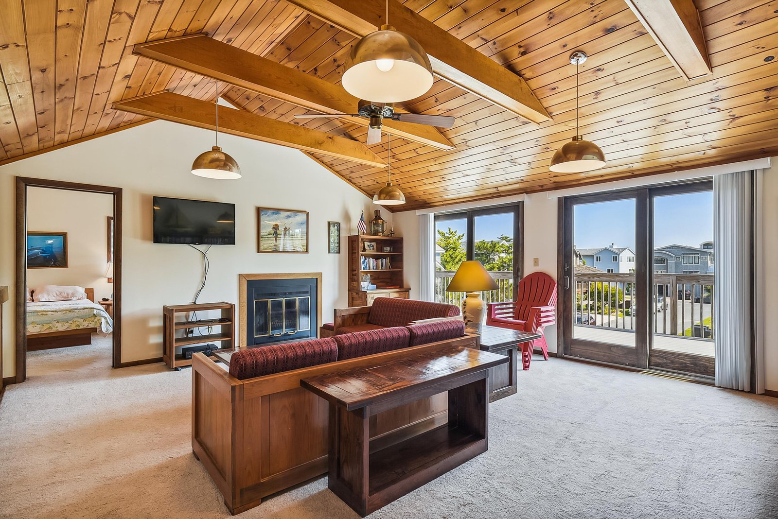 Relax under soaring wood-beamed ceilings while the ceiling fan keeps you cool and sunlight streams in through your private balcony doors, framing peaceful neighborhood views.