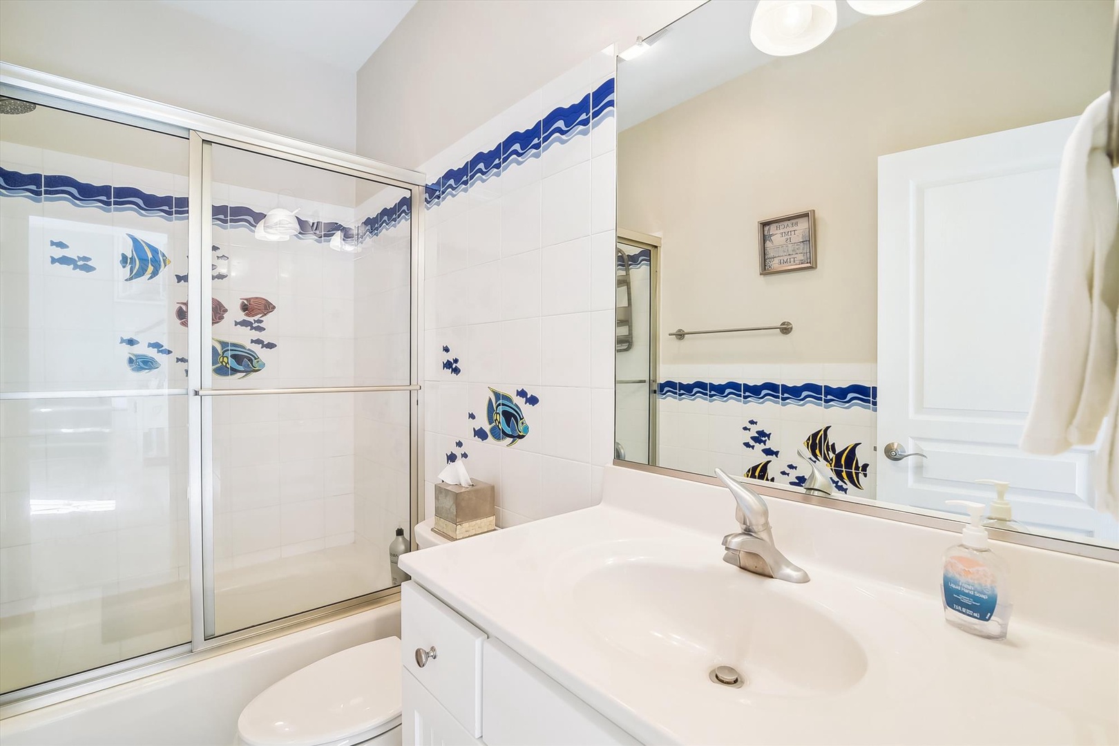 Refresh in your ocean-themed bathroom with tropical fish tiles and spacious glass shower.
