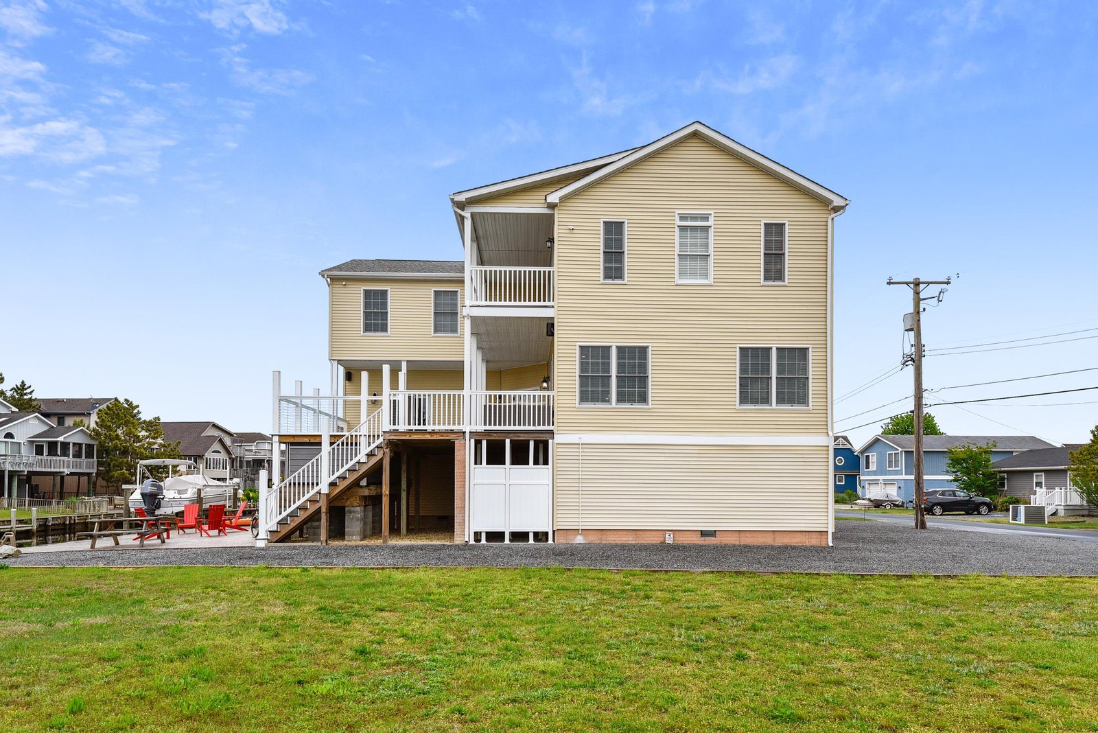 A spacious waterfront property with elevated decks and a grassy yard, perfectly positioned in a residential neighborhood near the water's edge.