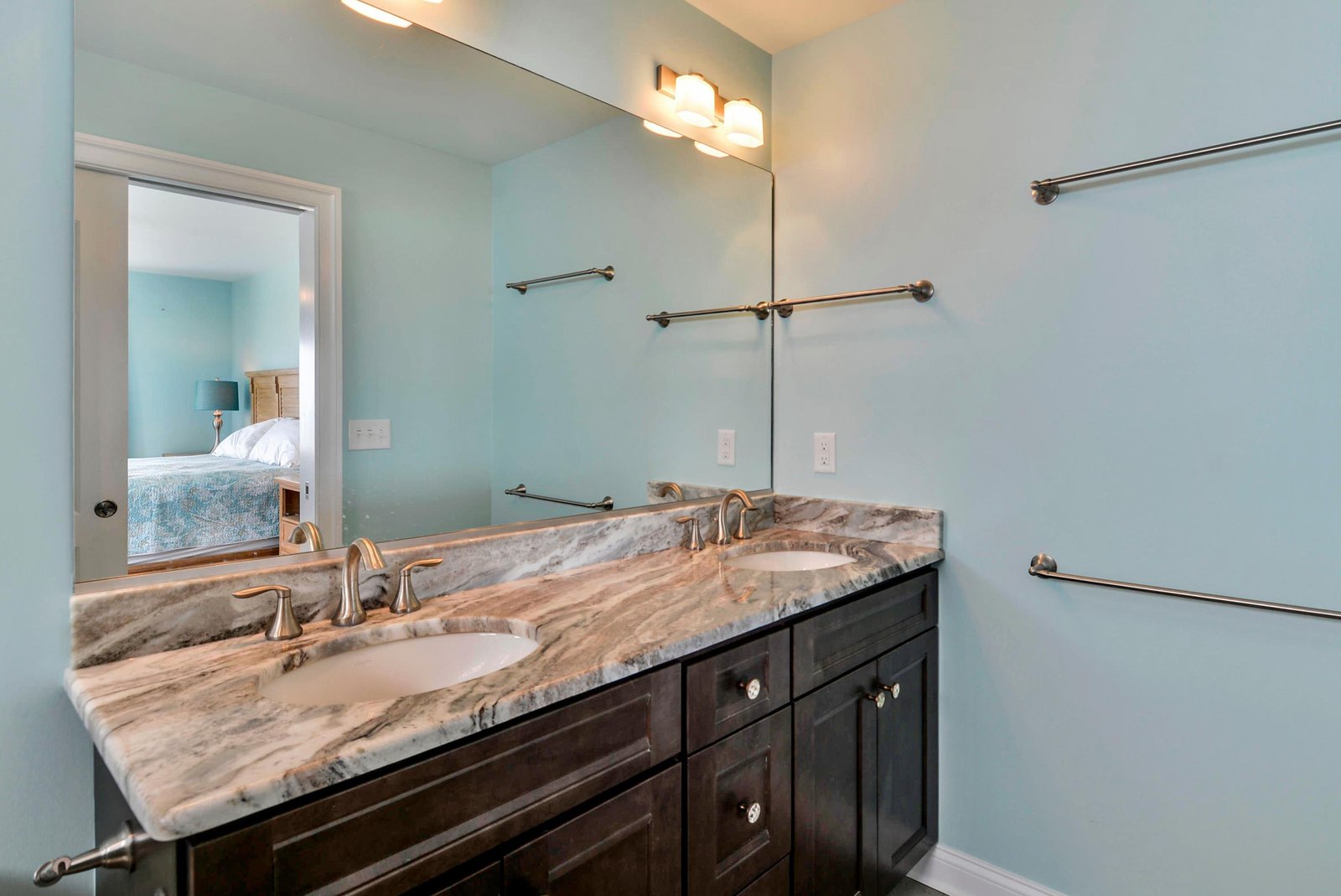 Your elegant bathroom features a dual-sink vanity with stunning marble countertops, soft lighting, and convenient towel bars—everything you need to freshen up in style.