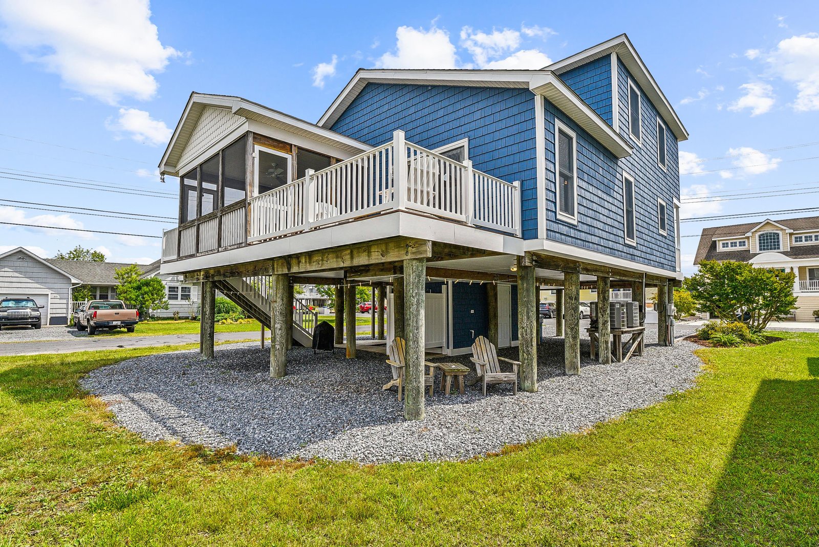 Distinctive blue-shingled beach house elevated on sturdy pilings with inviting deck and covered outdoor gathering area. Classic coastal charm in a quiet residential setting, perfect for your seaside escape.