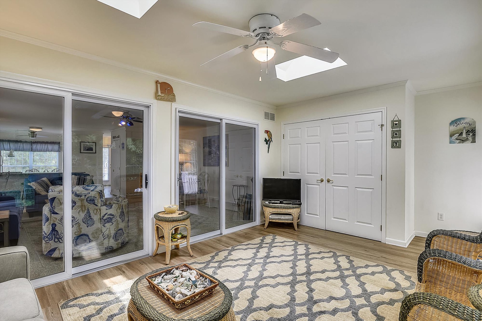 Relax in your bright, open living space with a ceiling fan overhead, patterned rug underfoot, and sliding glass doors that bring in natural light and easy access to outdoor areas.
