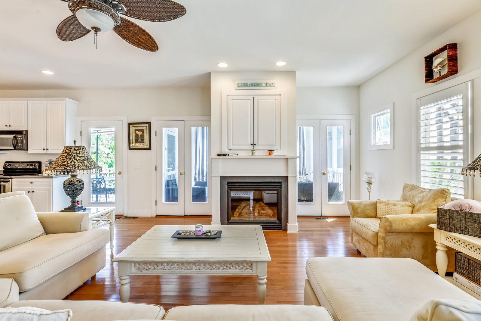 Unwind in your spacious living area where coastal elegance meets comfort, featuring a warm fireplace, gleaming hardwood floors, and breezy French doors inviting natural light throughout.