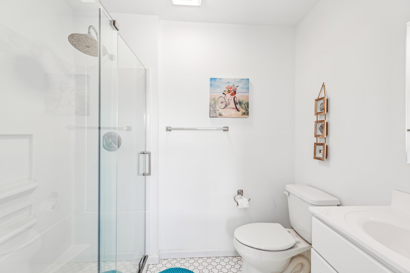 Step into your bright, spotless bathroom with a rainfall shower, crisp white tiling, and a cheerful coastal vibe that makes every morning feel fresh.