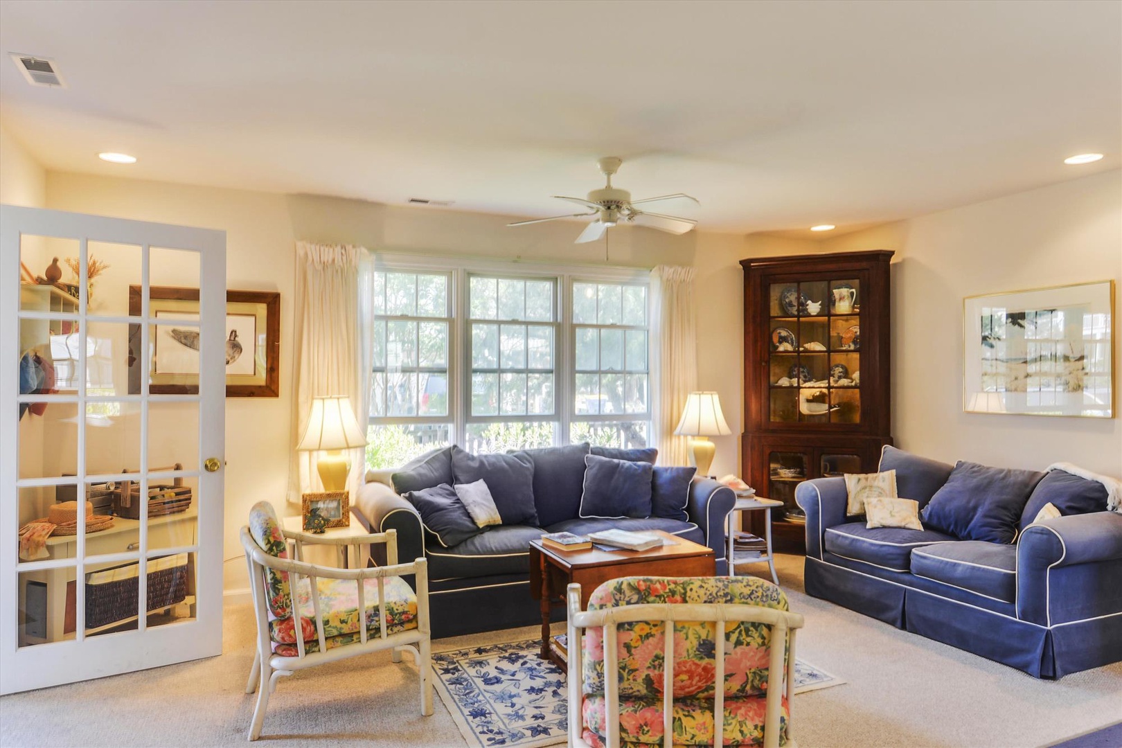 Settle into this inviting living room with plush navy sofas, charming antique details, and natural light streaming through large windows. Your perfect retreat for relaxation.