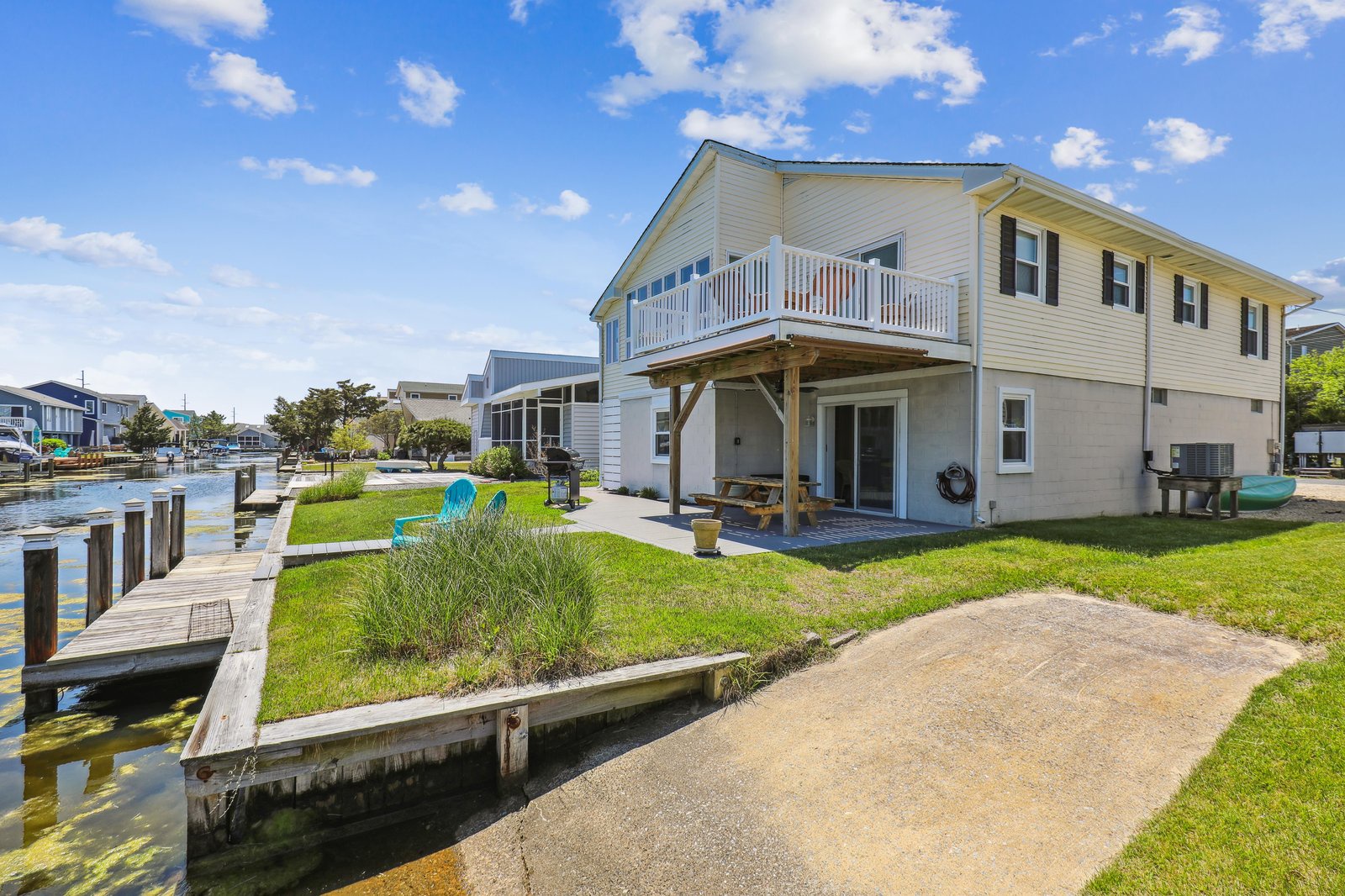 Charming waterfront home featuring direct access to calm canal waters from your private dock, plus a spacious upper-level balcony and covered patio perfect for relaxing by the water.
