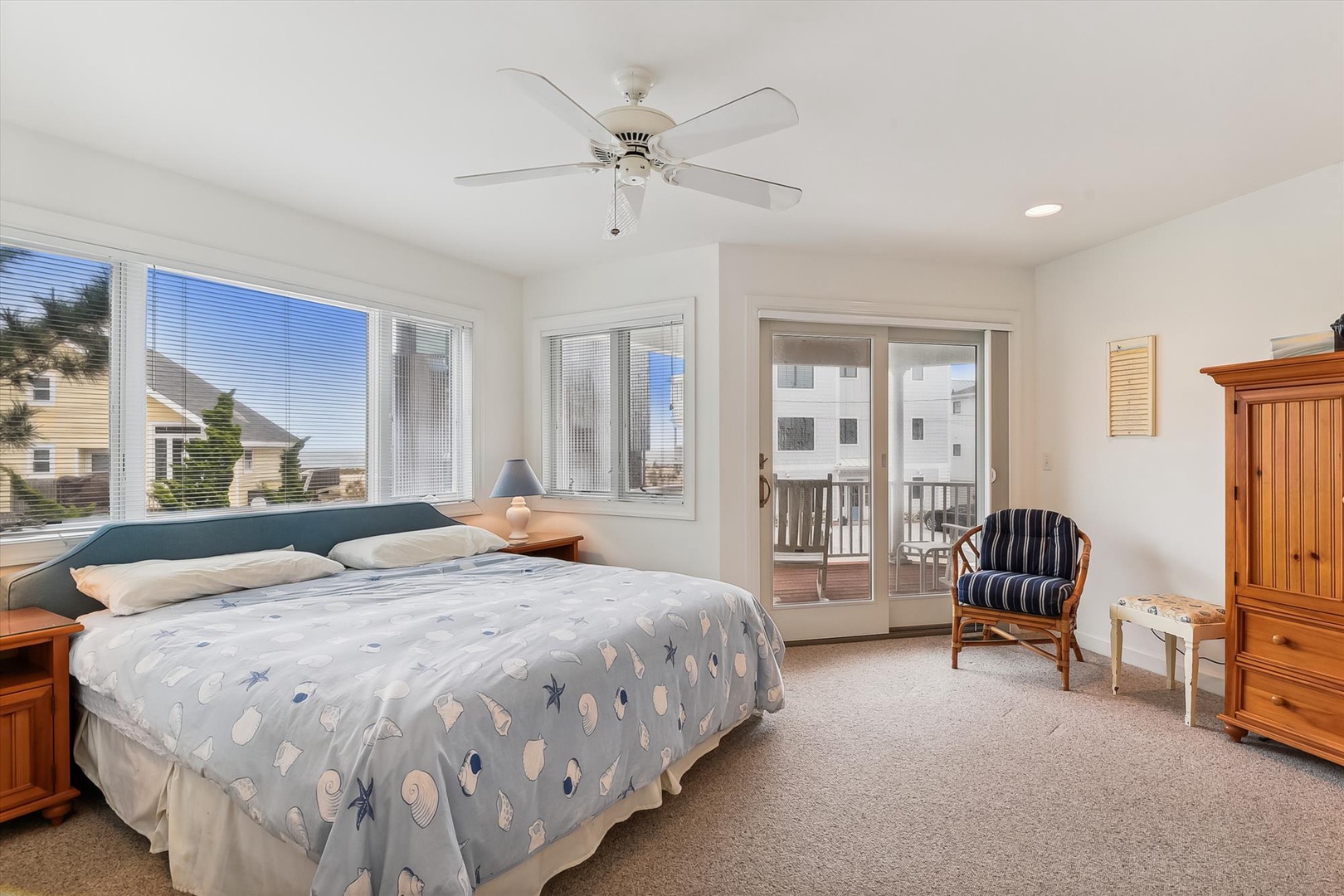 Drift off in this bright coastal bedroom with breezy ceiling fan, ocean-themed bedding, and your own private balcony just steps away.