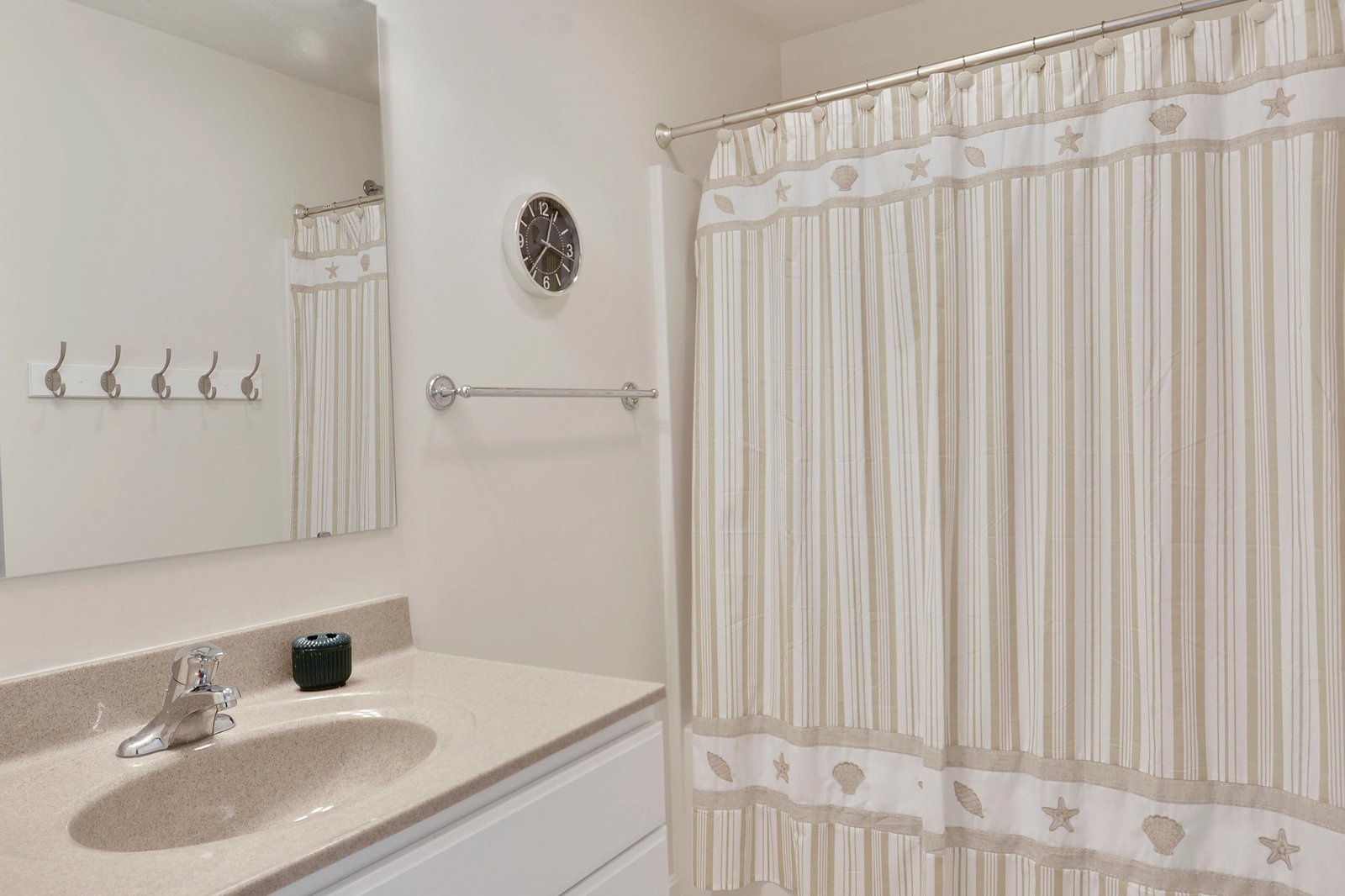 Step into your private bathroom featuring coastal charm with seashell-accented curtains, clean countertops, and everything you need to refresh after a day at the beach.