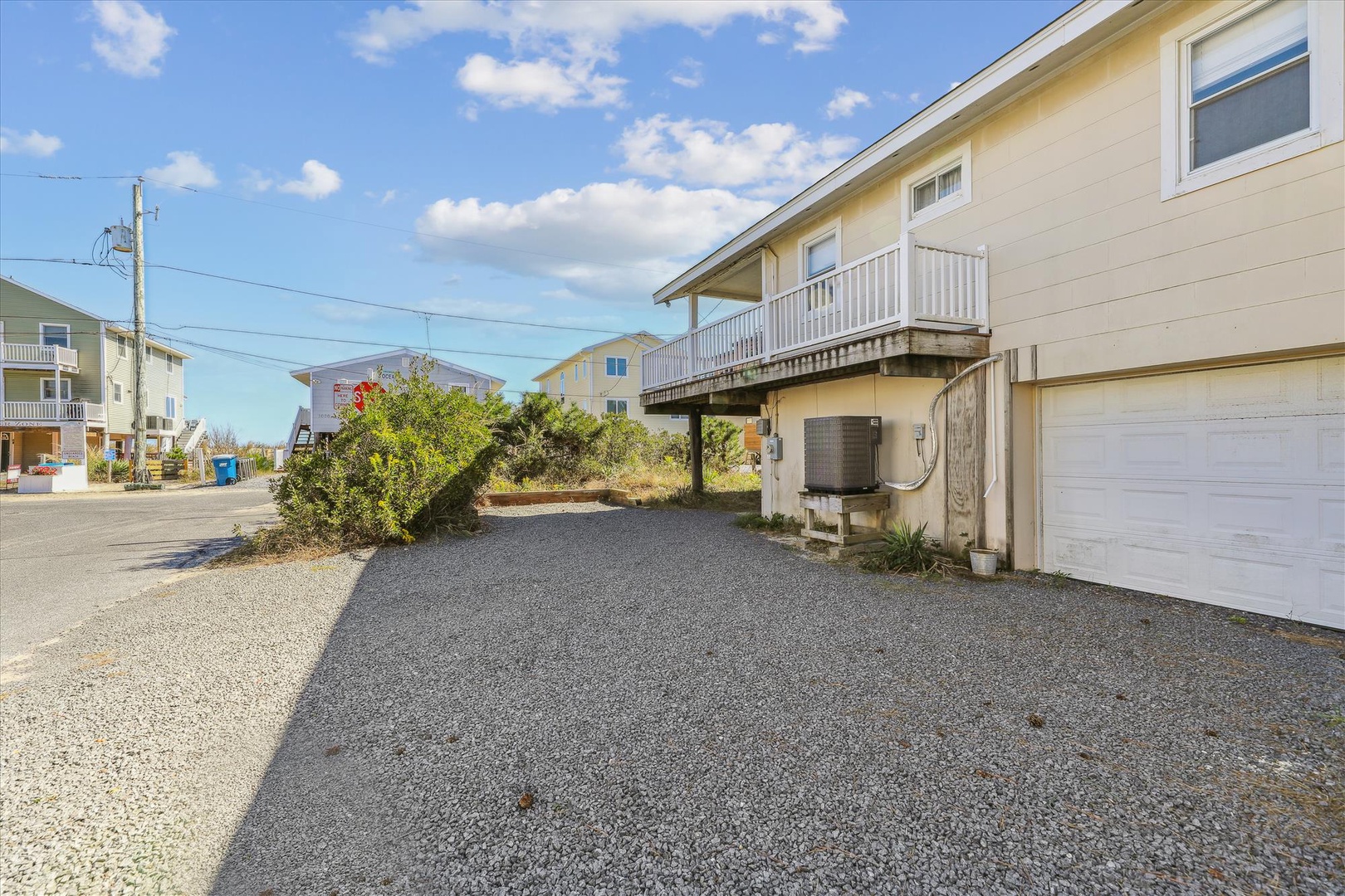 A peaceful coastal neighborhood with beach house charm, featuring gravel parking for easy access and private outdoor space nestled among similar vacation properties.