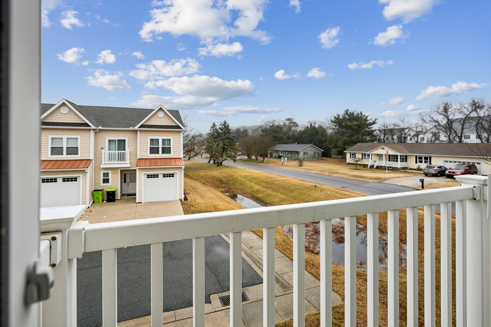 Peaceful residential neighborhood with well-maintained homes and landscaped yards visible from this upper-level balcony on a beautiful day.